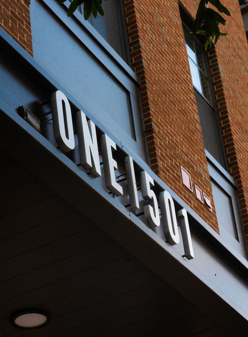 Close-up of a building sign reading "ONE 1501" on a brick facade.