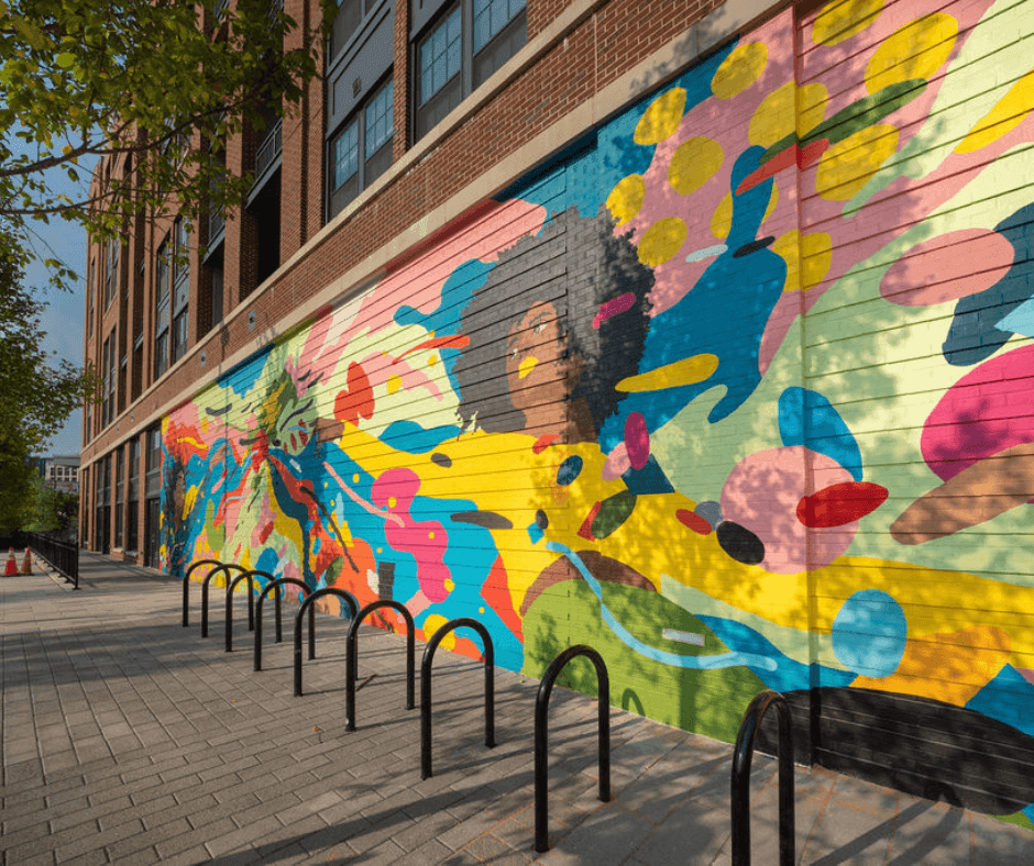 Colorful mural featuring abstract shapes and figures on a brick wall.