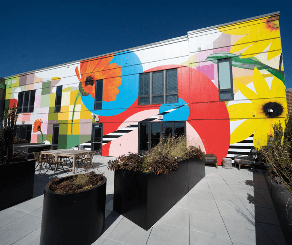 Vibrant mural on a building wall, featuring colorful floral designs and geometric shapes.