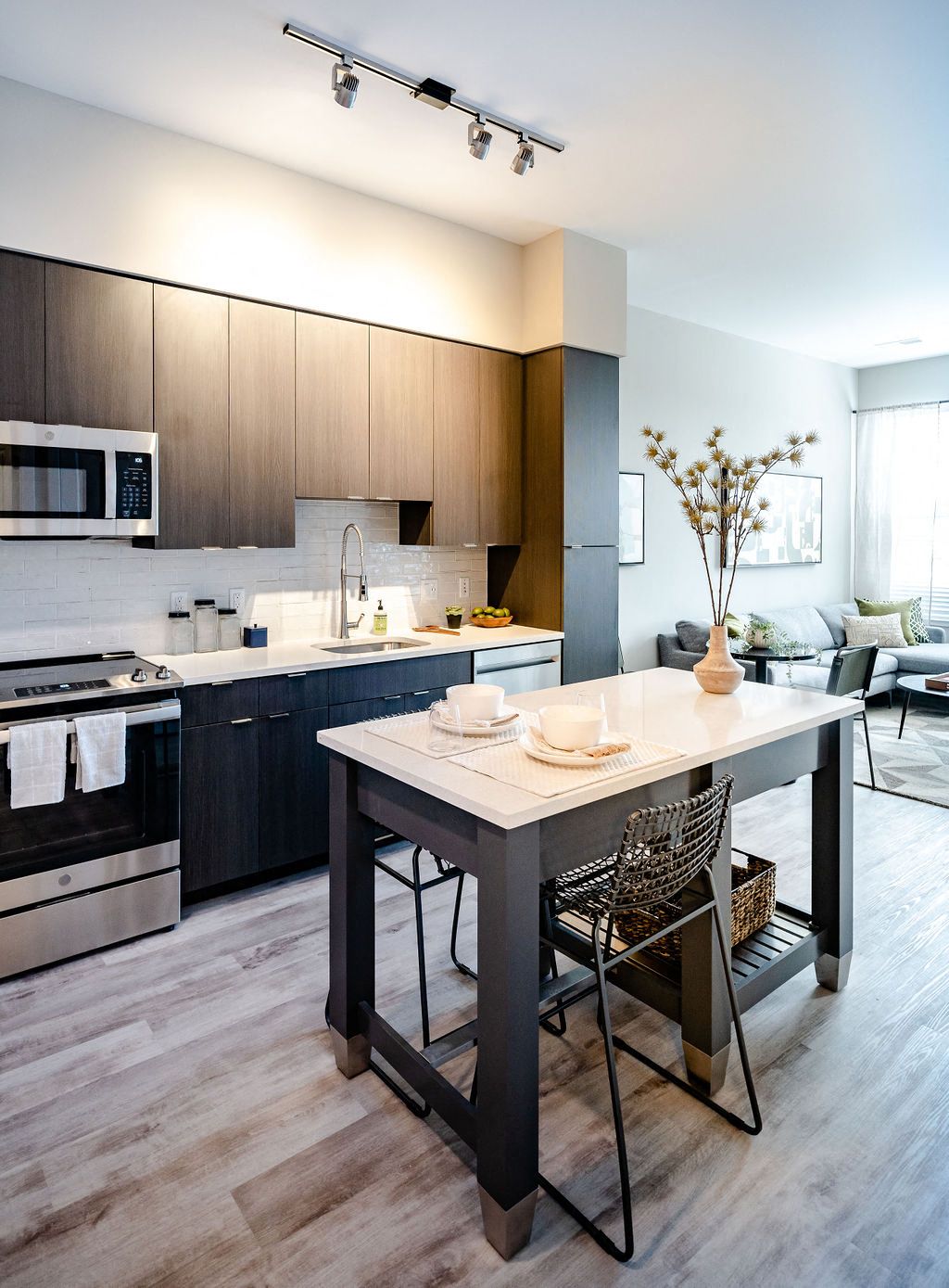 Modern kitchen with dark cabinetry, stainless steel appliances, and a small dining table.