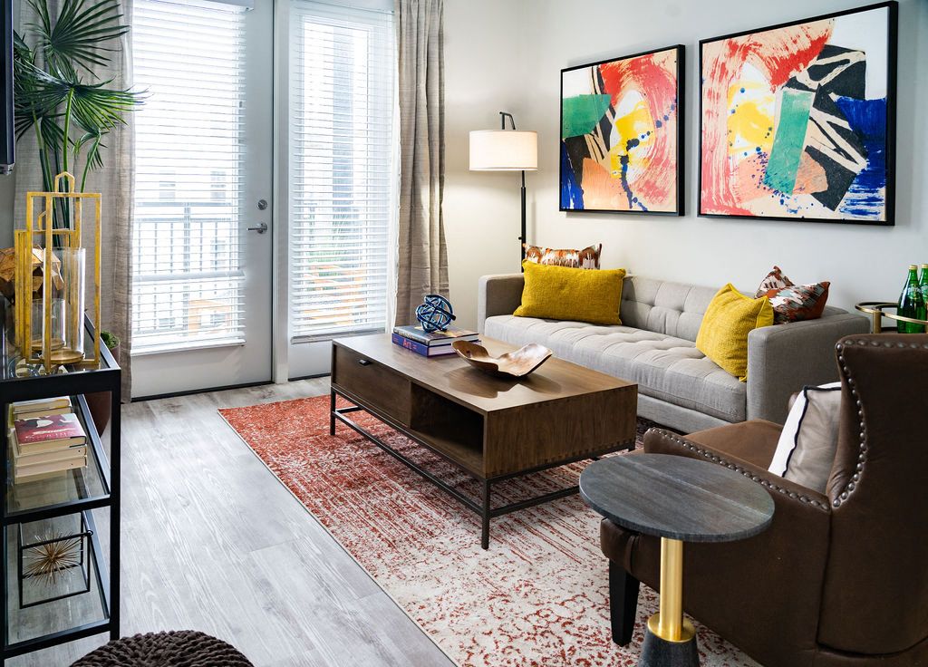 Modern living room with colorful art, a sofa, coffee table, and natural light from large windows.