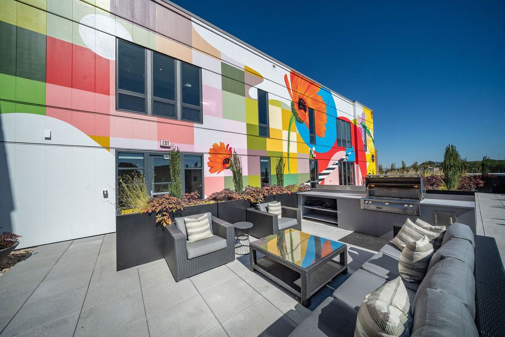 Vibrant mural on a modern building with a stylish outdoor seating area.