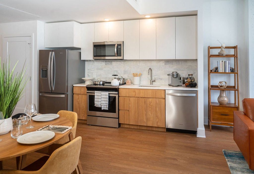 Modern kitchen with wooden cabinets, stainless appliances, and a dining table.