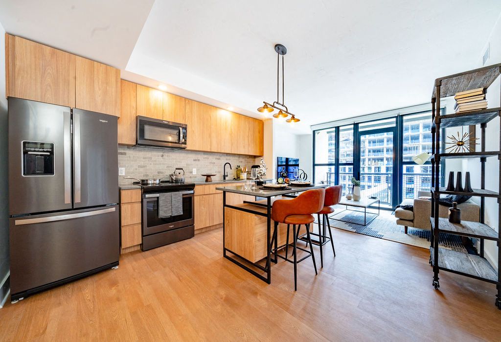 Modern kitchen with wooden cabinets, stainless steel appliances, and an island with seating.