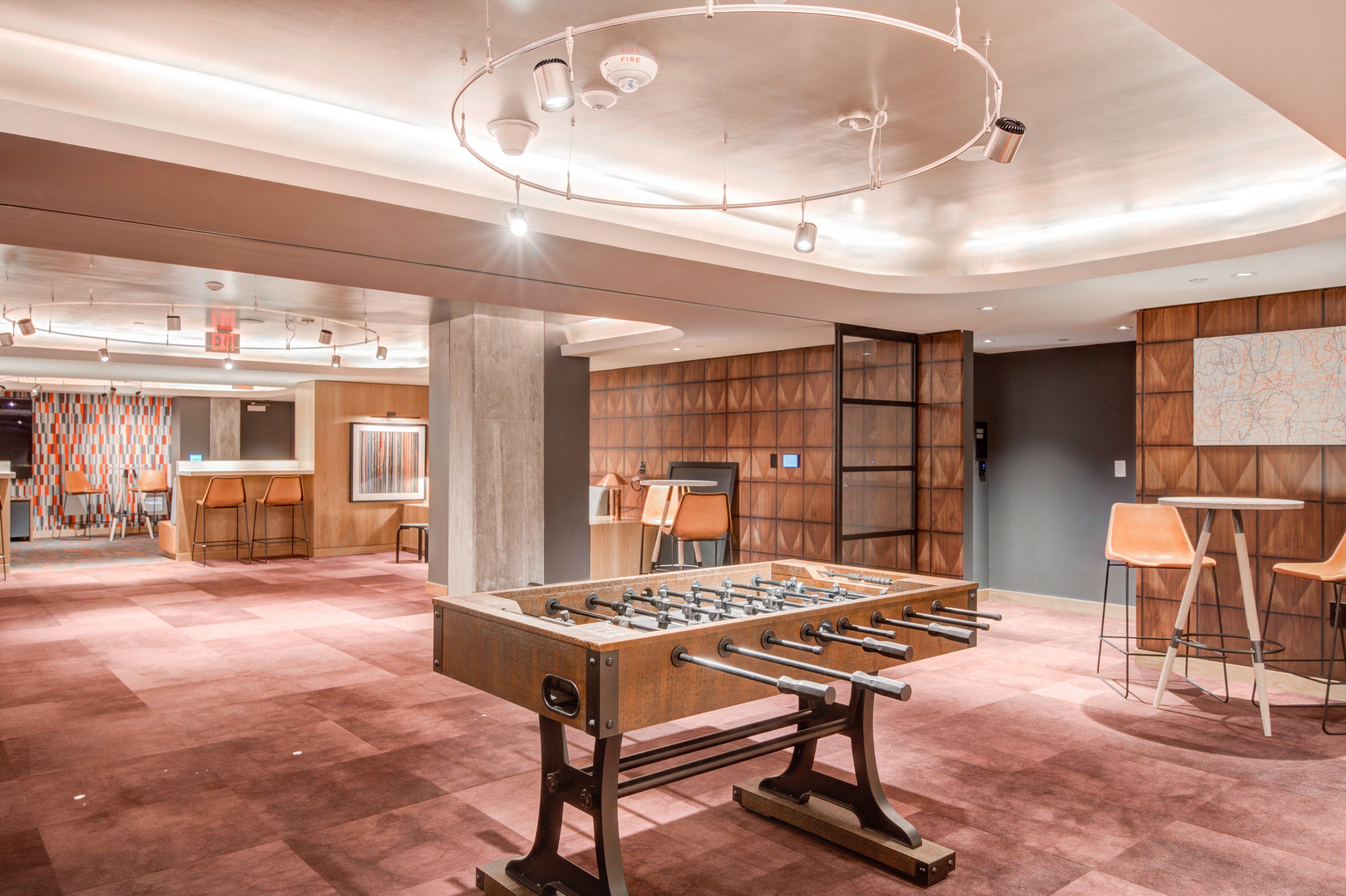 Modern lounge with a foosball table, bar area, and stylish seating.