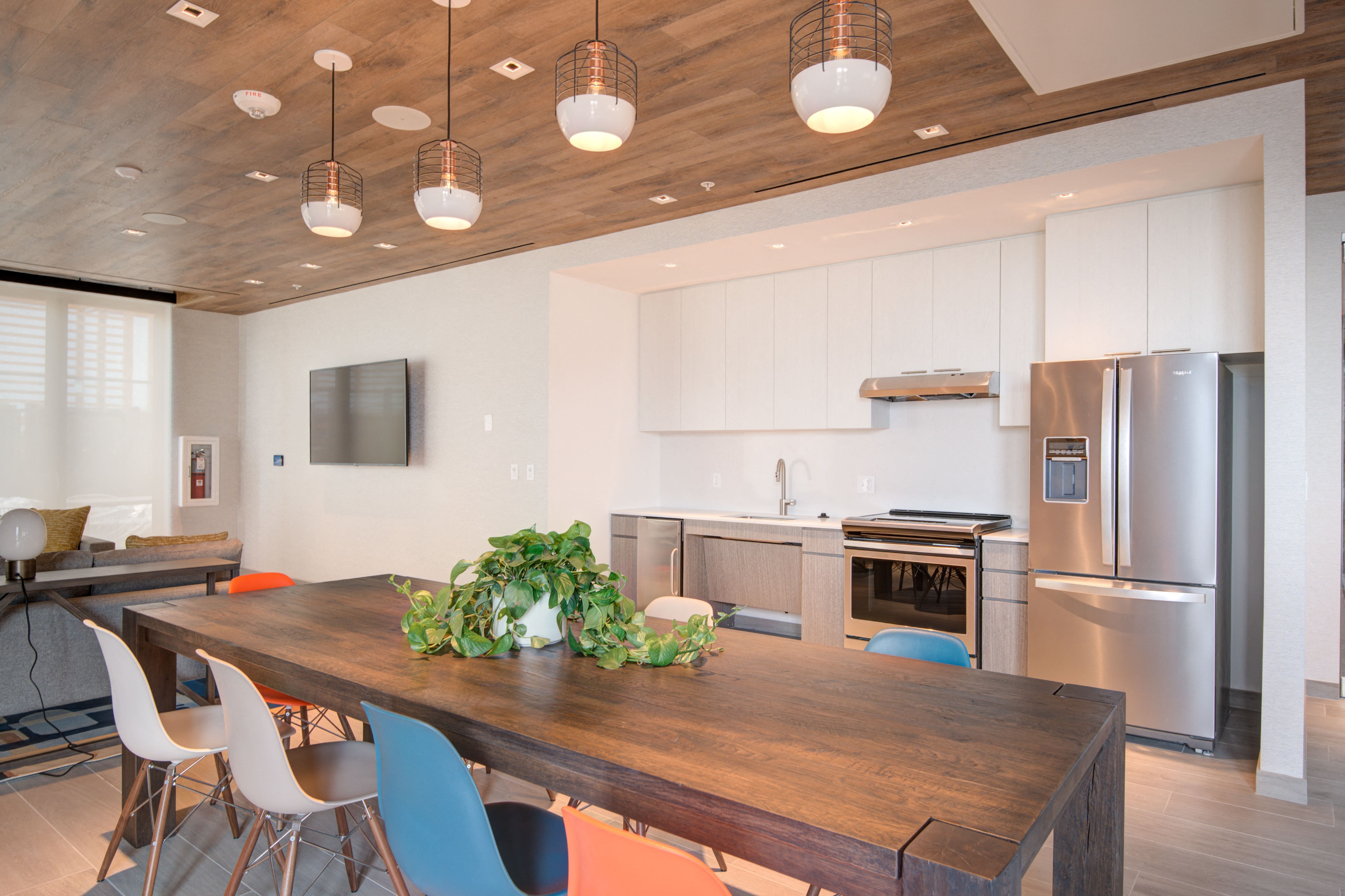 Modern kitchen with wooden ceiling, stainless appliances, and a large dining table.