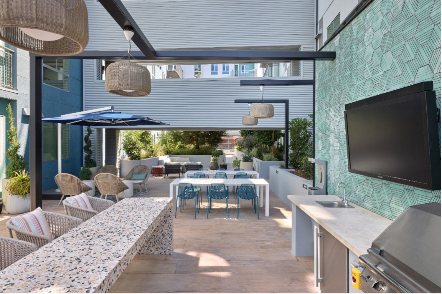Outdoor patio with a modern kitchen, dining area, and decorative plants.