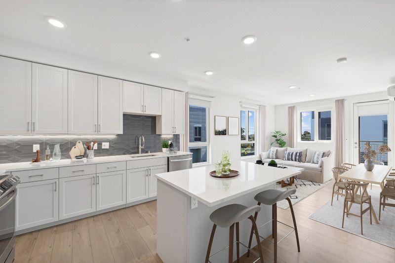 Modern kitchen and dining area with white cabinetry and large windows.