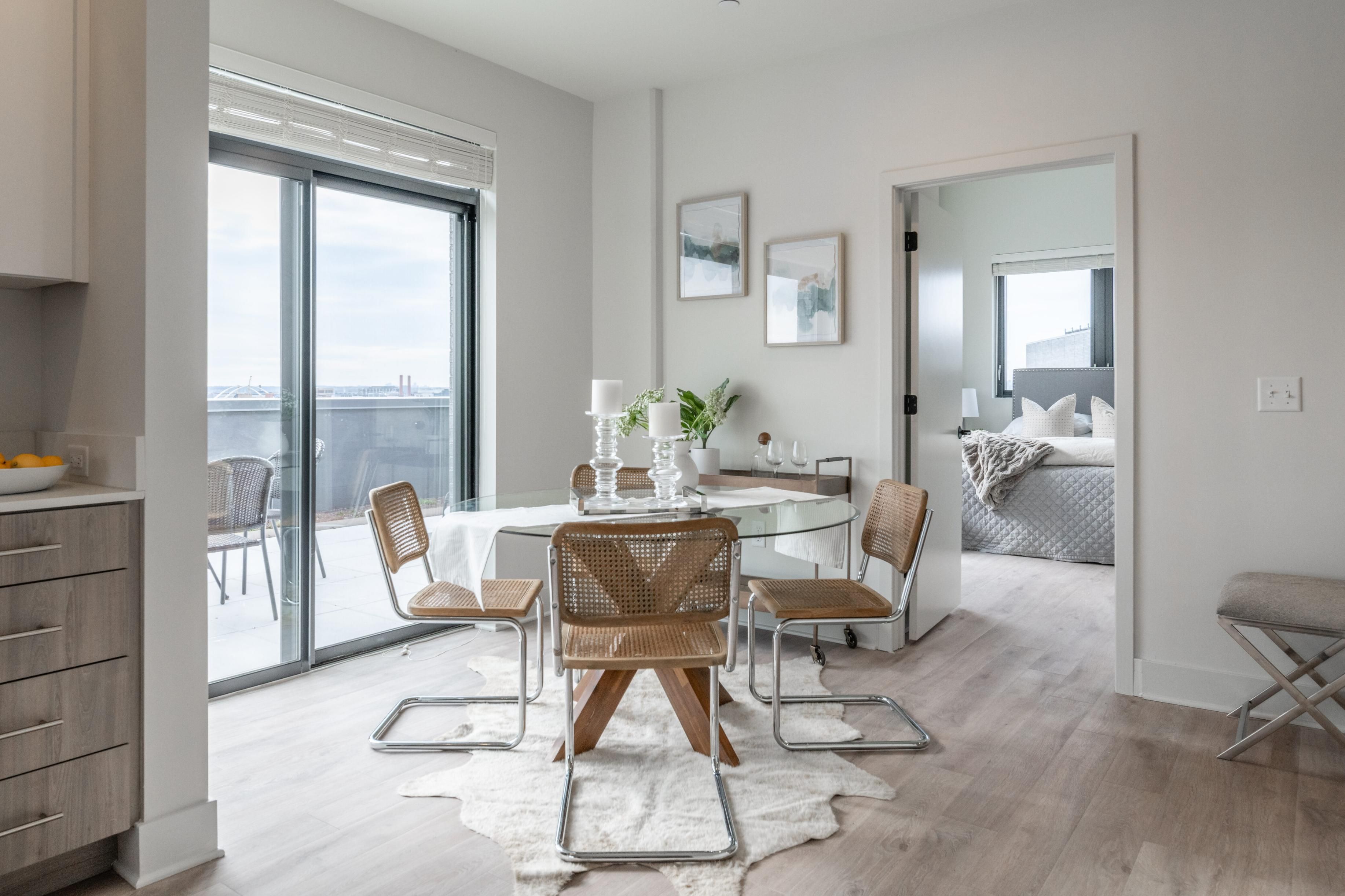 Modern dining area with glass table, chairs, and access to an outdoor balcony.