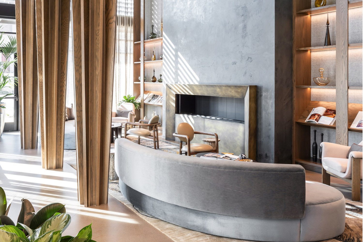 Contemporary lounge area with curved sofa, bookshelves, and natural light.