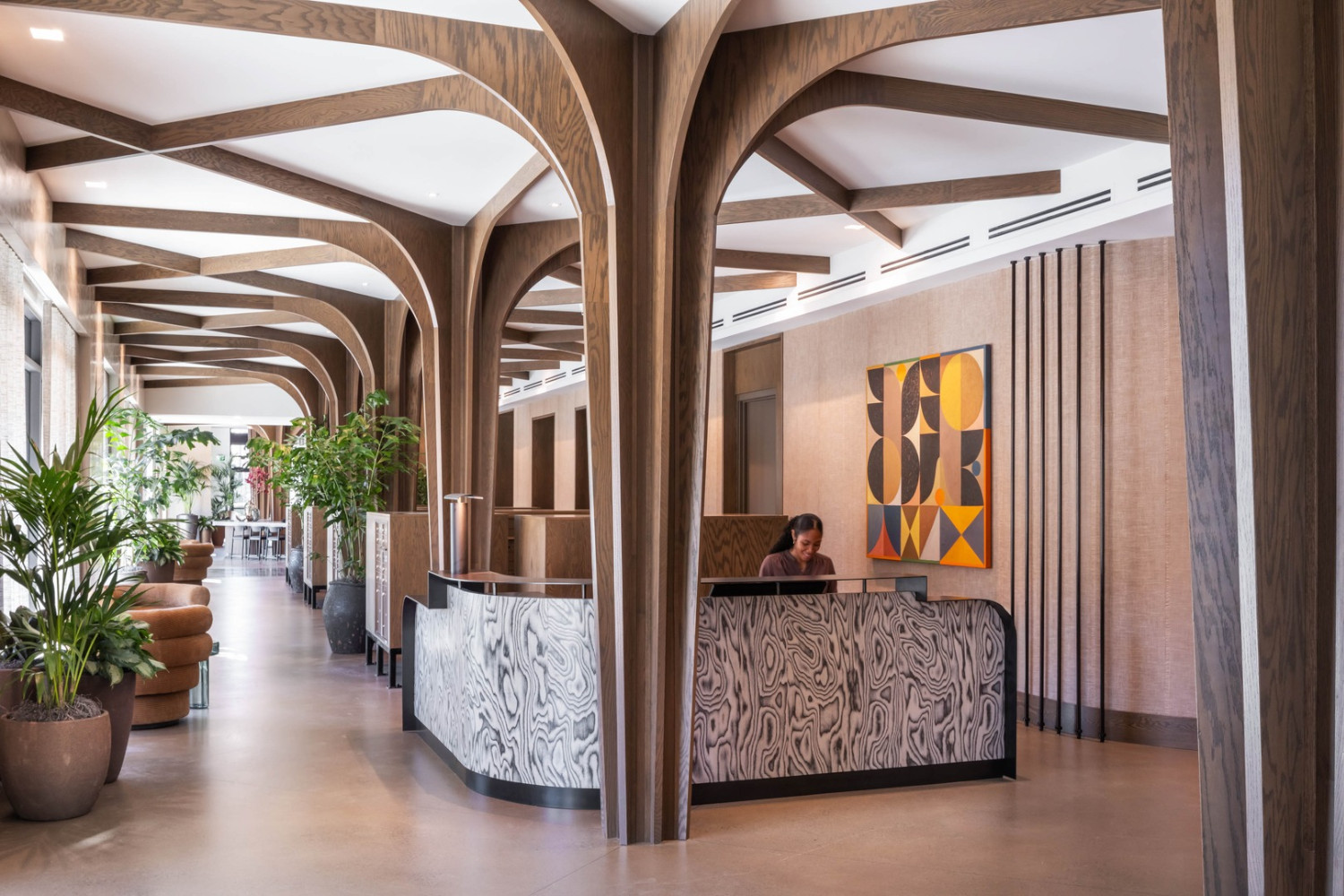 Modern lobby with wooden arches, plants, and a reception desk.