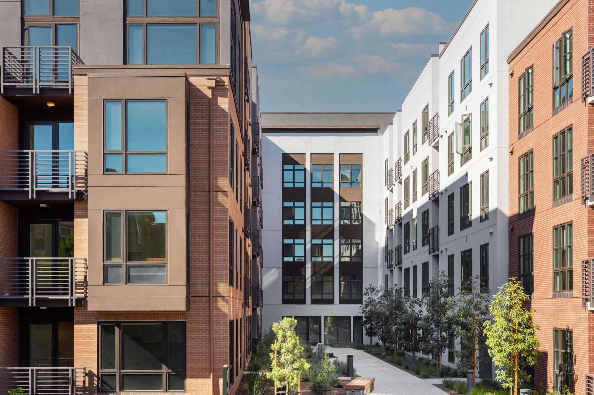 Modern multi-story apartment buildings with greenery in between.