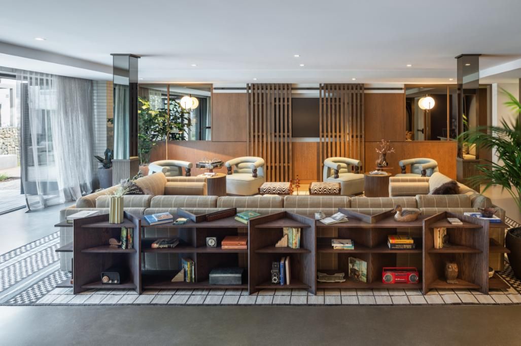 Modern lounge with a plush sofa, bookshelves, plants, and warm wood accents.