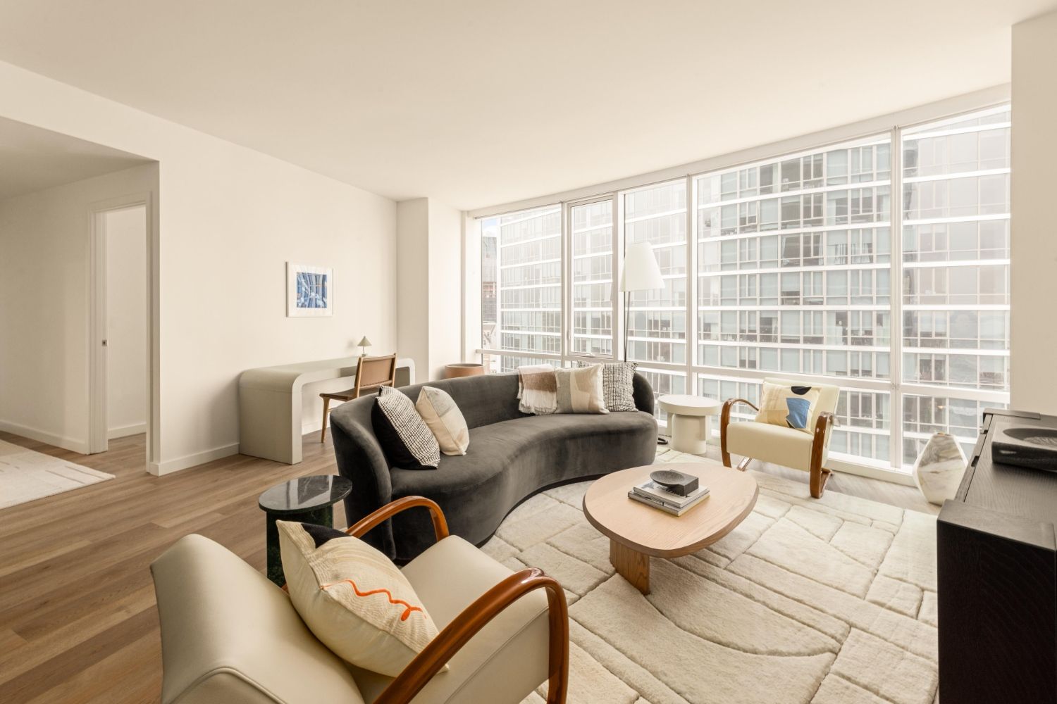 Modern living room with large windows, sleek furniture, and neutral colors.