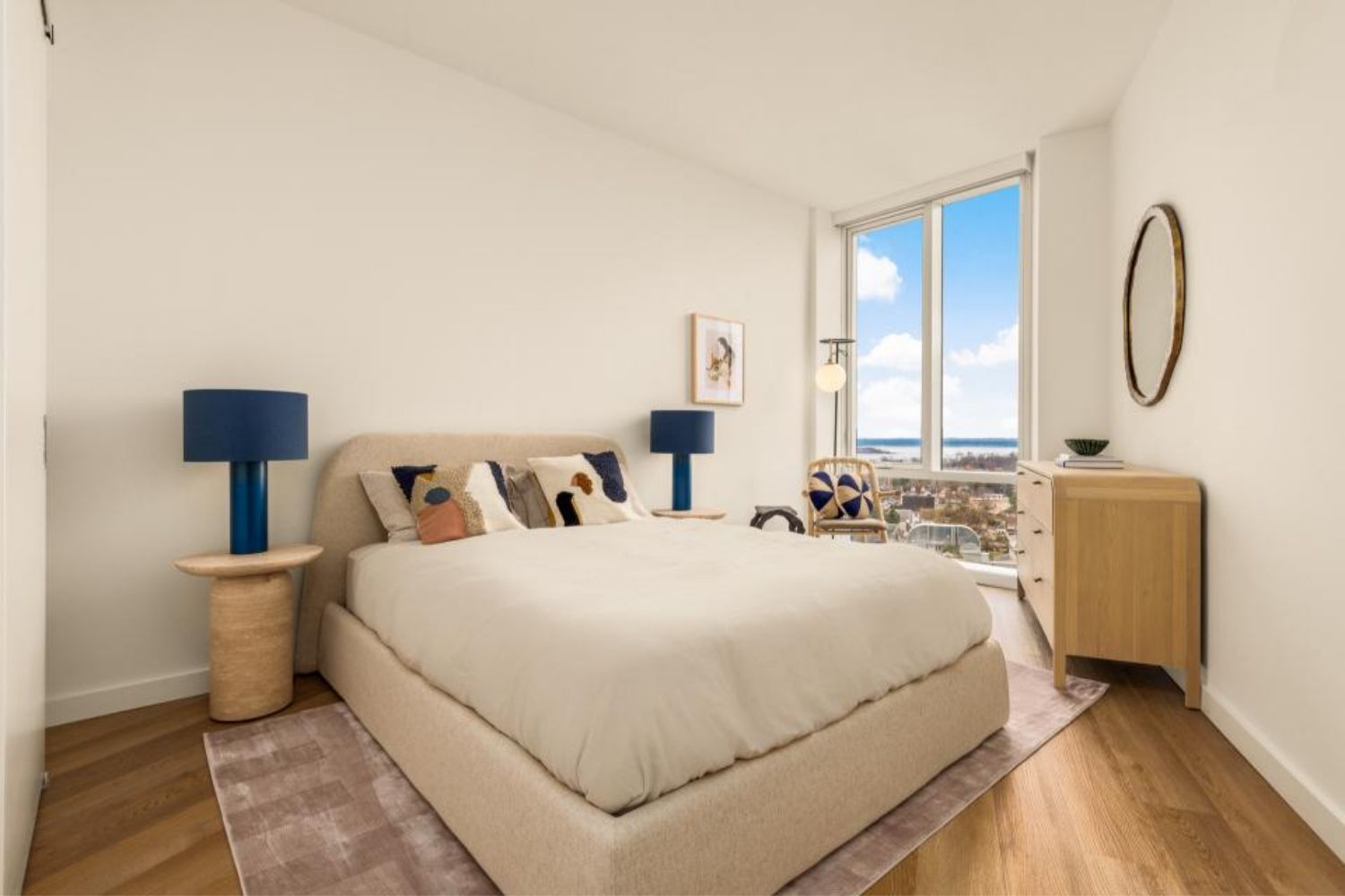 Modern bedroom with a bed, lamps, and large windows offering a view.