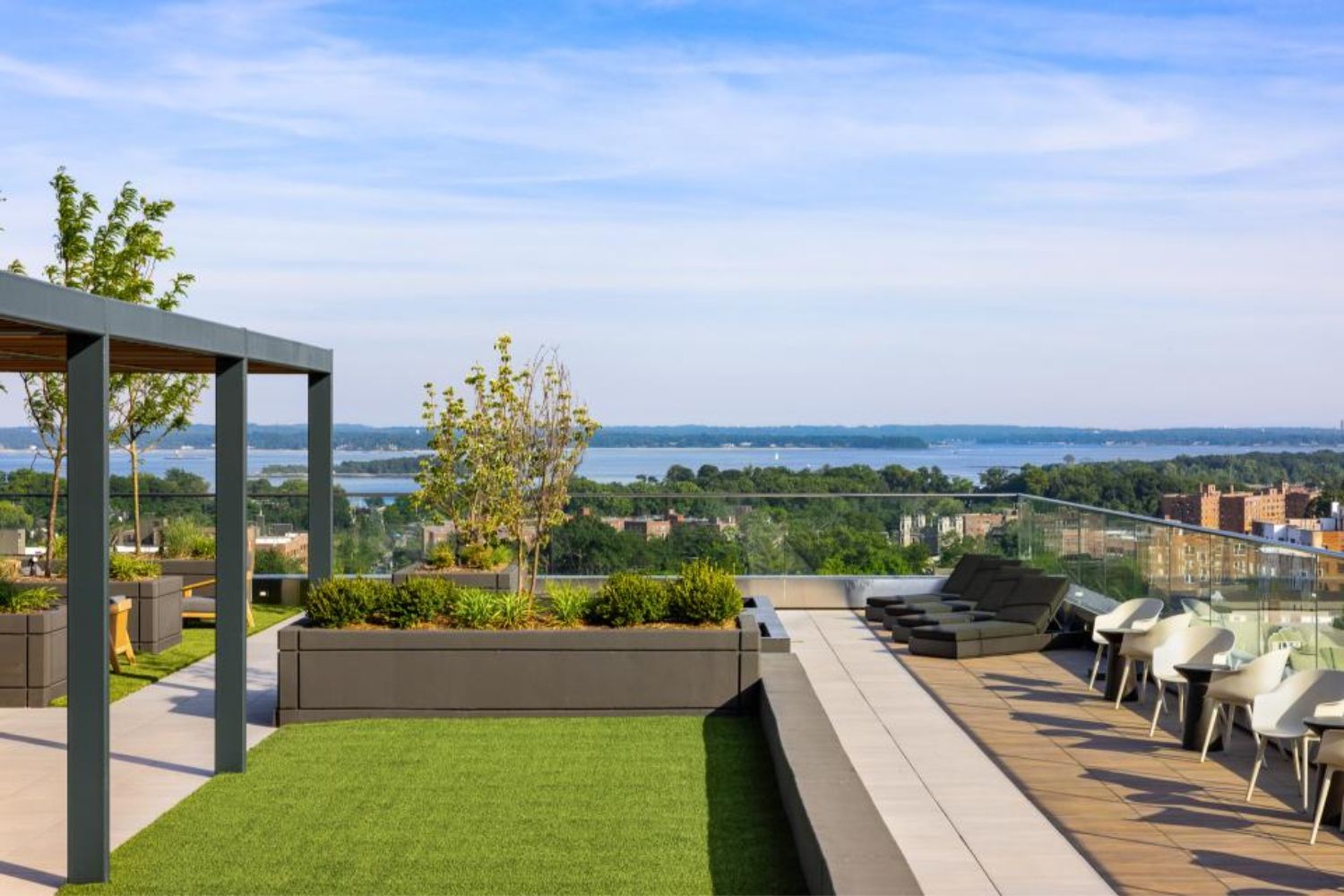 Rooftop terrace with greenery and seating, overlooking a scenic view of water and landscape.