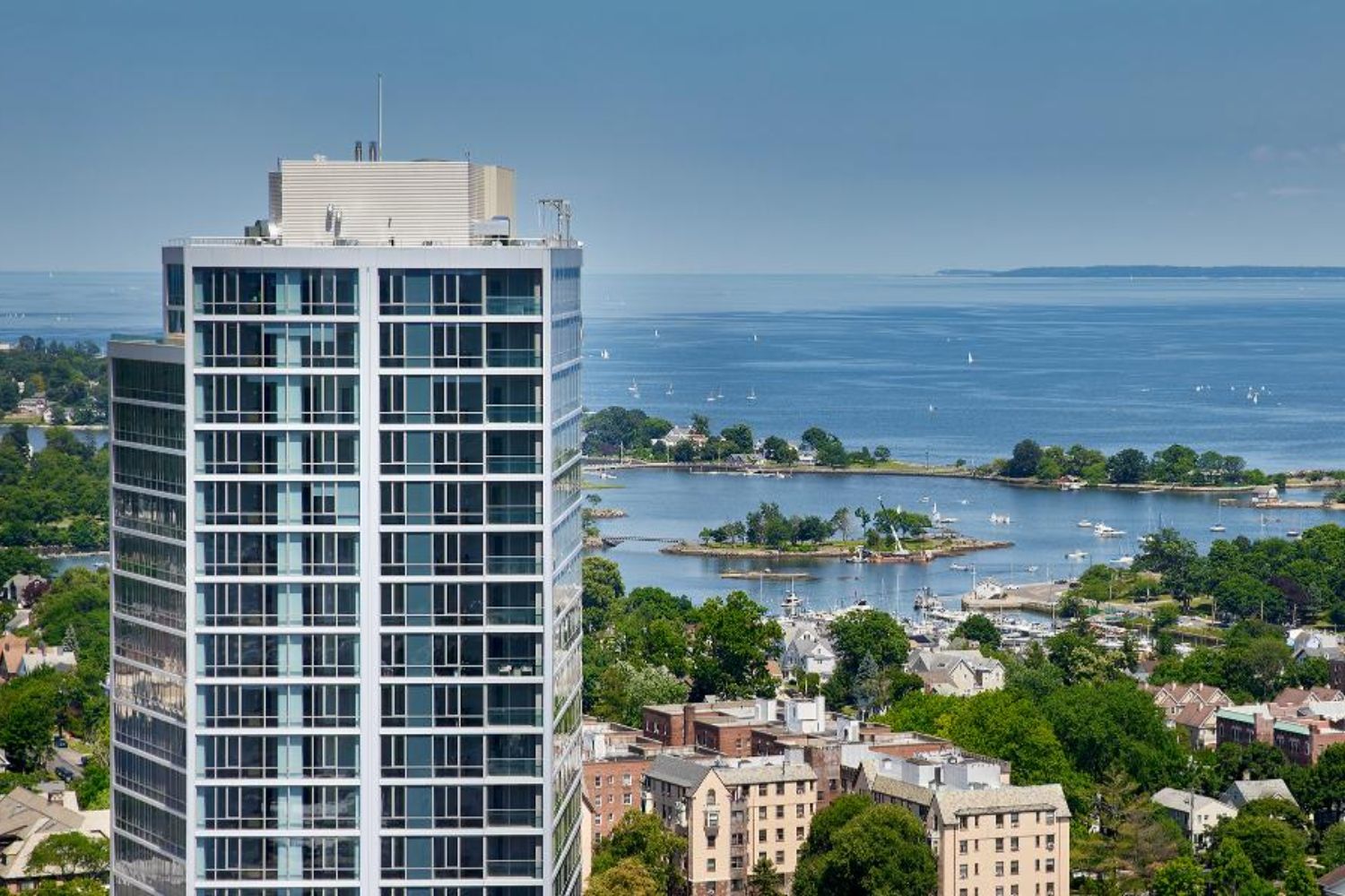 A modern building overlooking a serene waterfront and lush landscape.