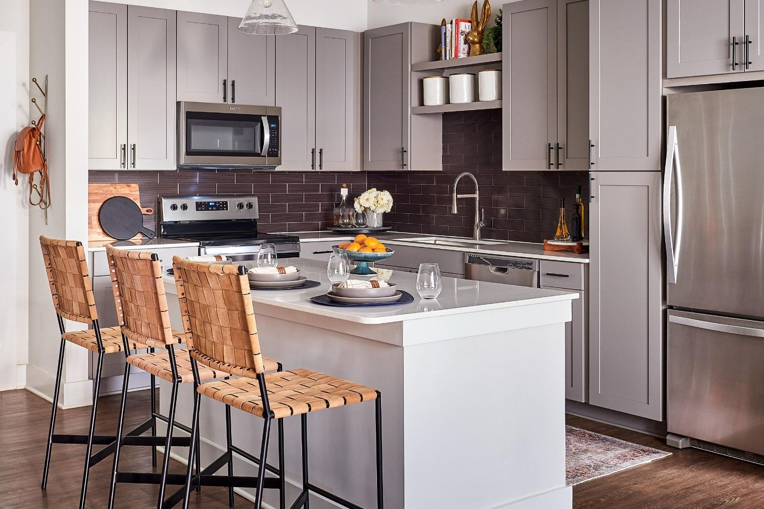 Kitchen with gray cabinets, brown tile backsplash, island seating, and pendant lighting