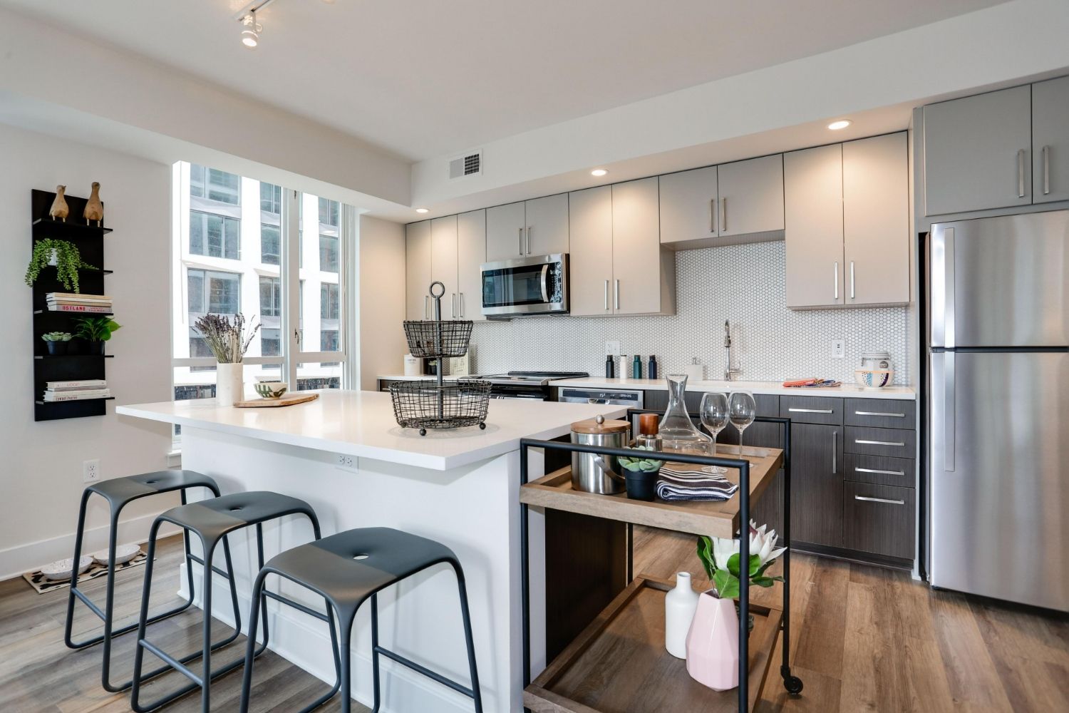 Modern kitchen with two-tone cabinets, island seating, bar cart, and stainless appliances