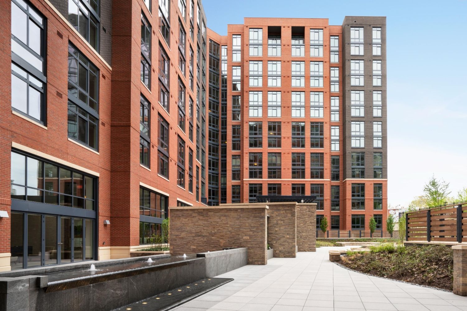Brick apartment courtyard with water feature, stone privacy walls, and modern landscaping