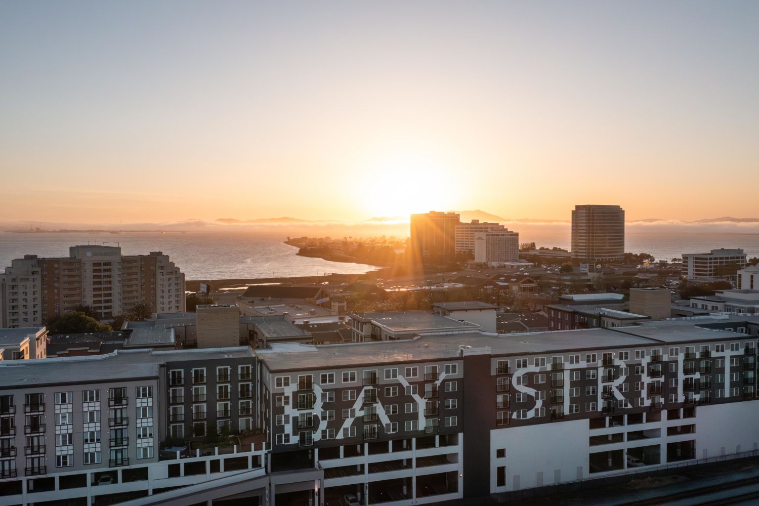 Sunset over a cityscape with "HAY STREET" displayed on a building.