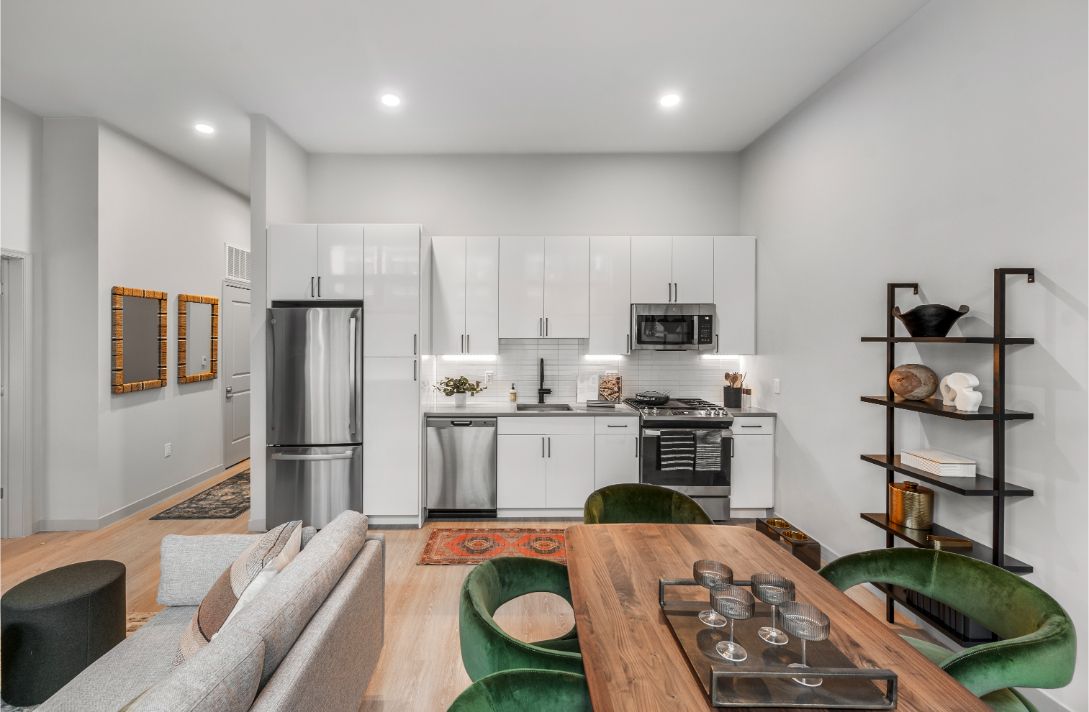 Contemporary kitchen with white cabinets, green chairs, wood table, and open shelving