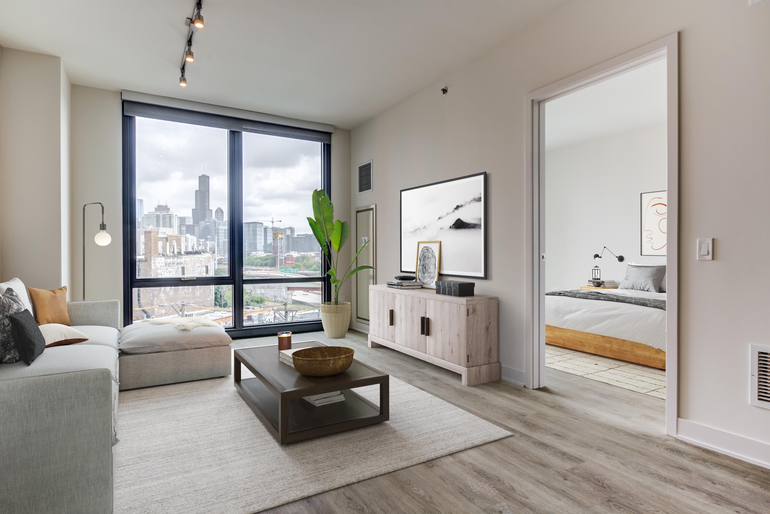 Modern living room with a skyline view, featuring a couch, coffee table, and decorative plant.