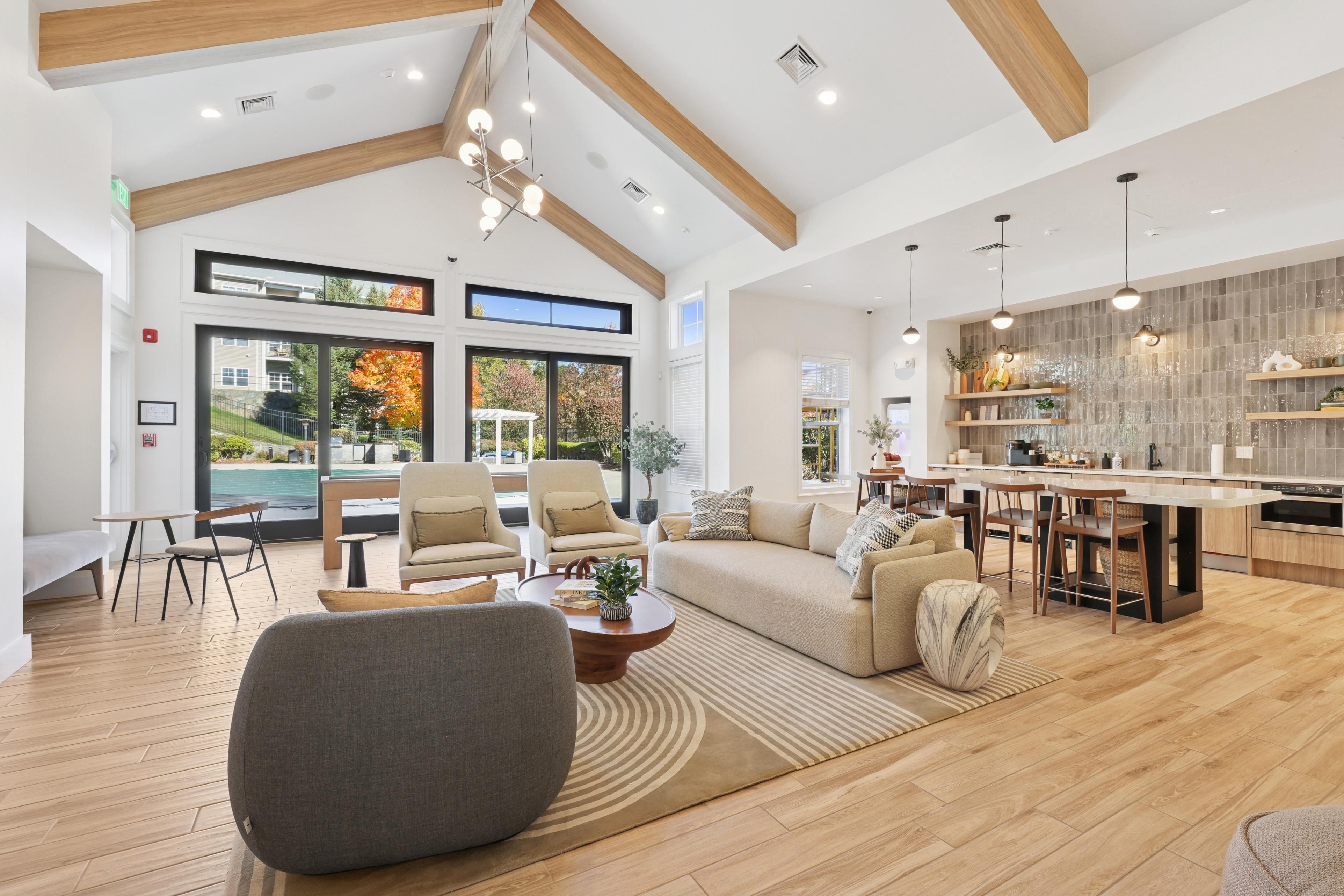 Modern living area with large windows, wooden beams, and stylish furniture.