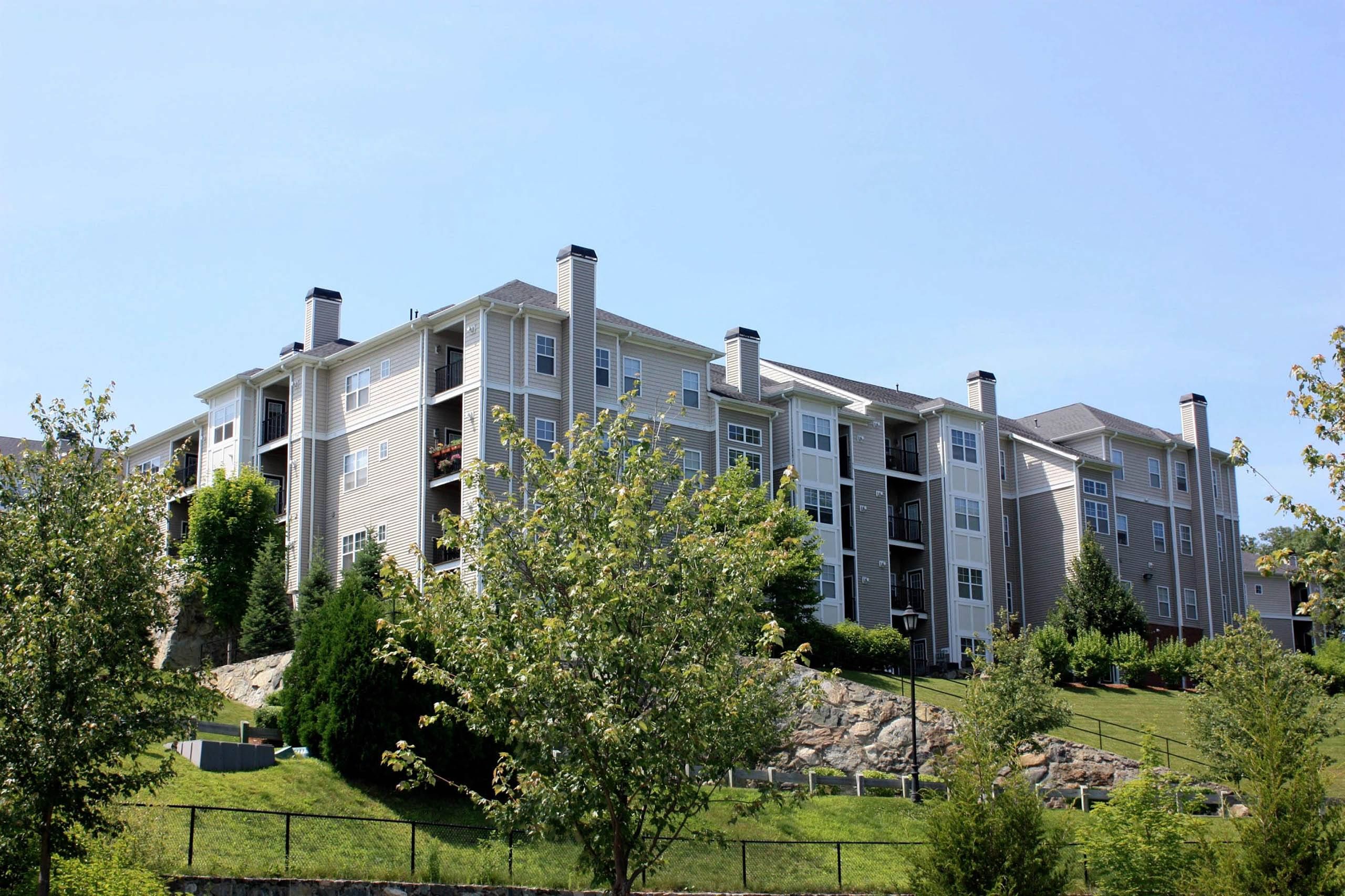 Modern apartment buildings against a clear blue sky, surrounded by greenery.