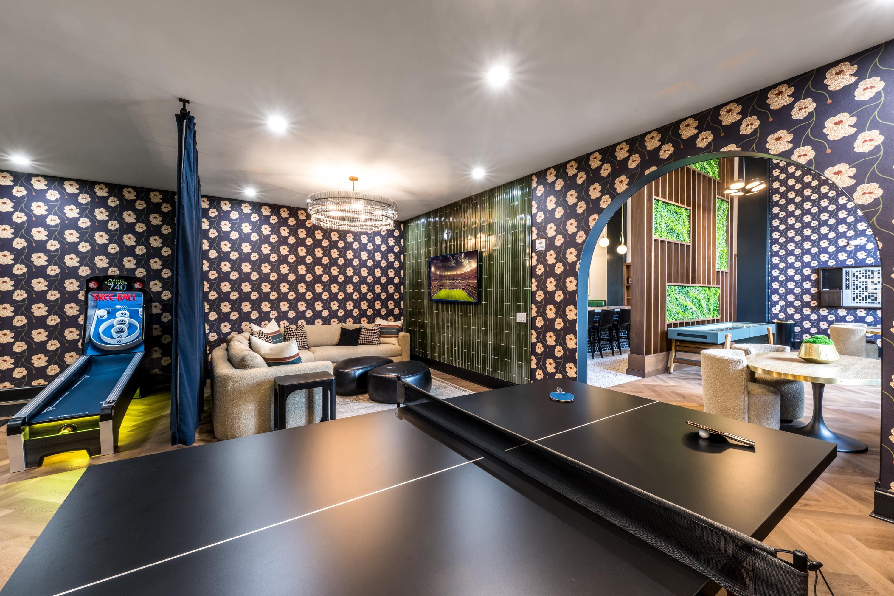 Modern game room featuring a ping pong table, plush seating, and playful wallpaper.