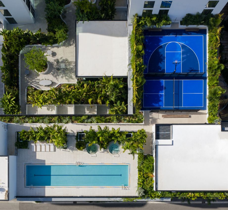Aerial view of a pool, tennis court, and landscaped areas.