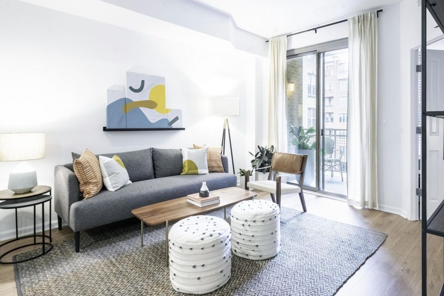 Bright living room with a gray sofa, wooden table, and balcony access.
