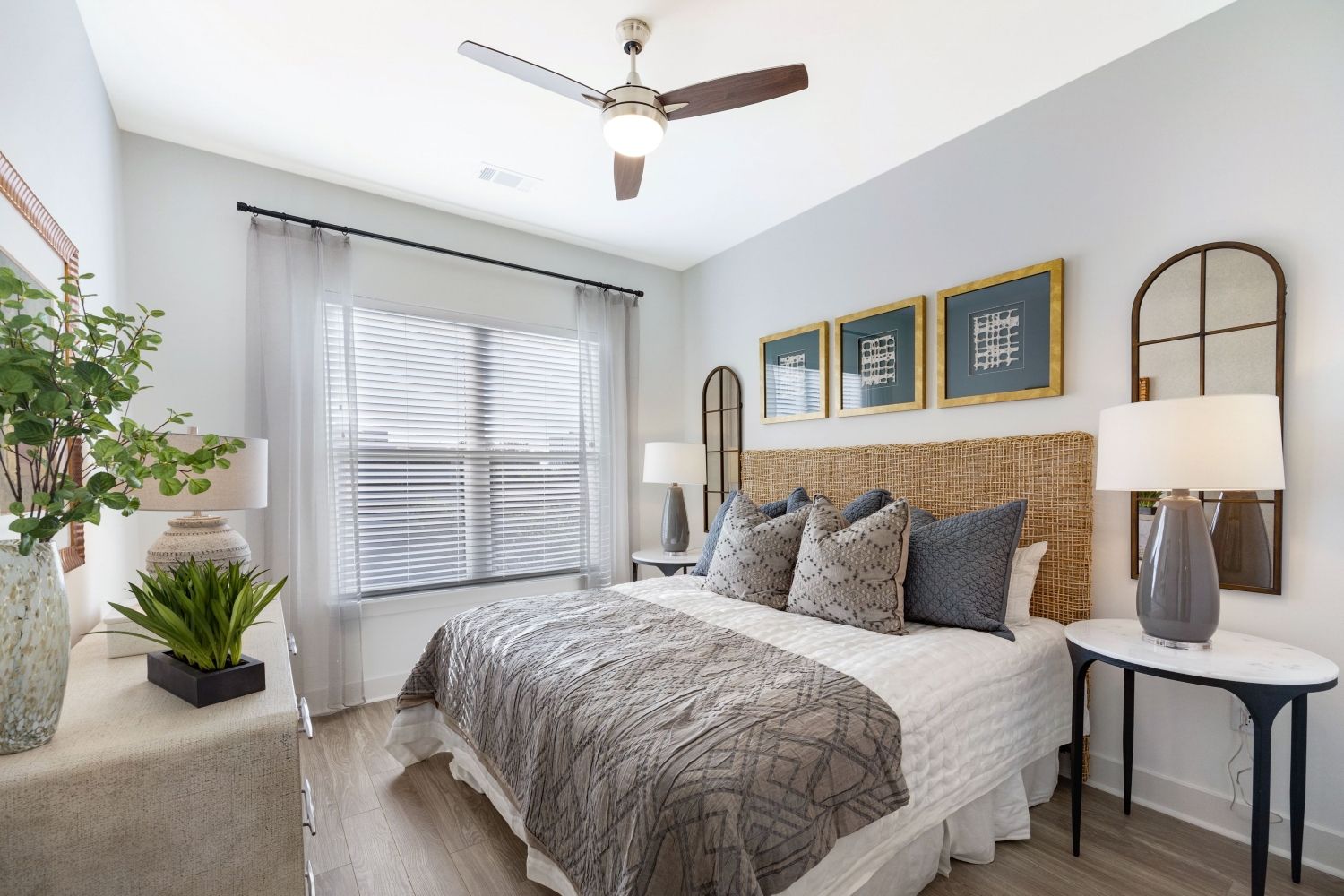 Cozy bedroom with a ceiling fan, large window, and neutral decor.