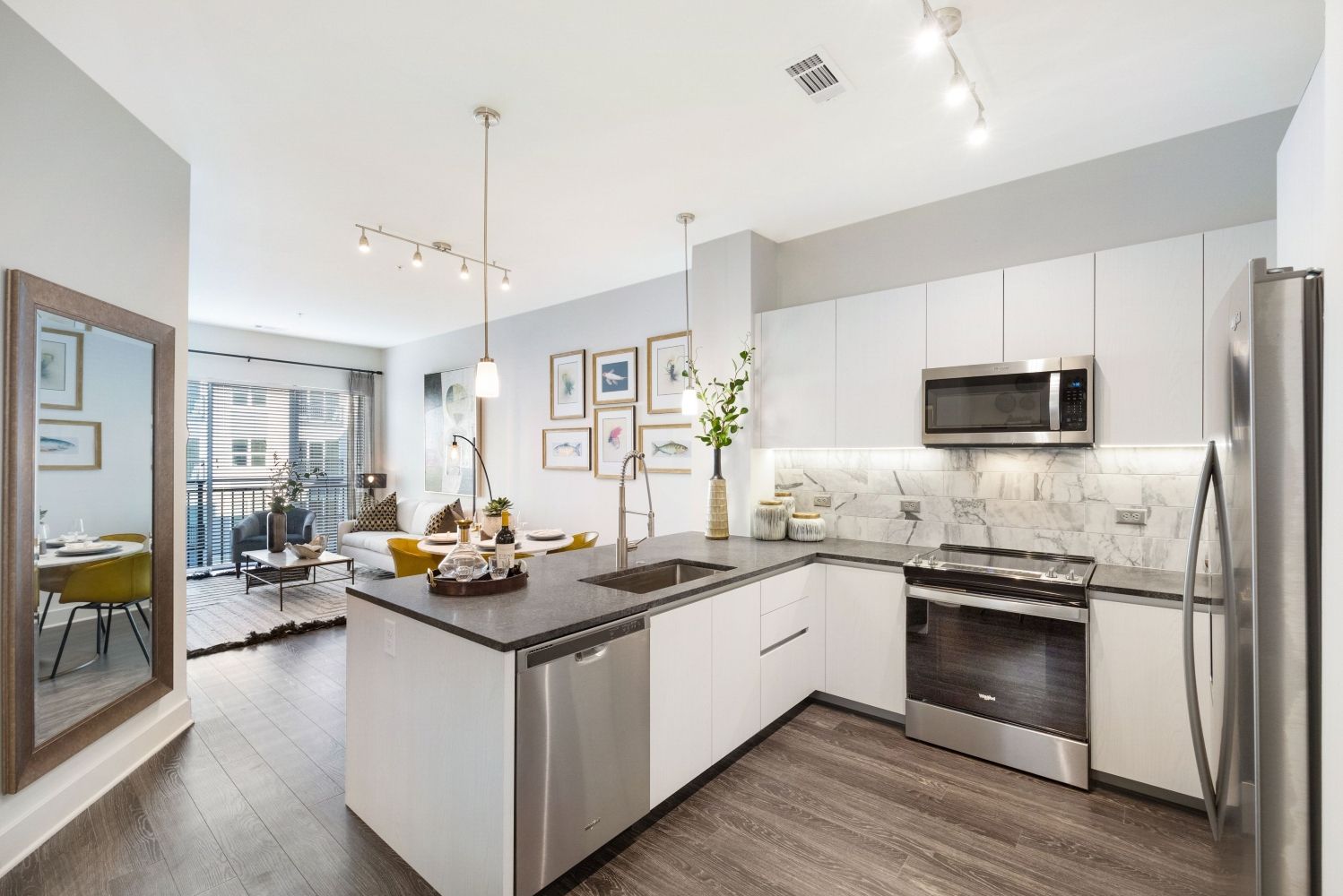 Modern kitchen with sleek appliances, light cabinetry, and an open living area.
