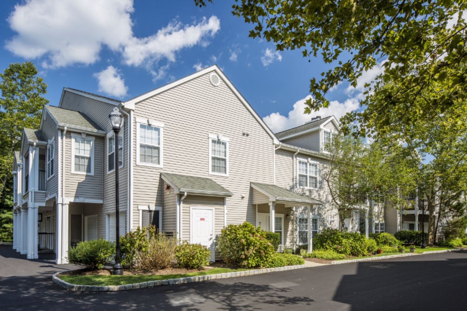 Modern apartment building surrounded by greenery and blue sky.