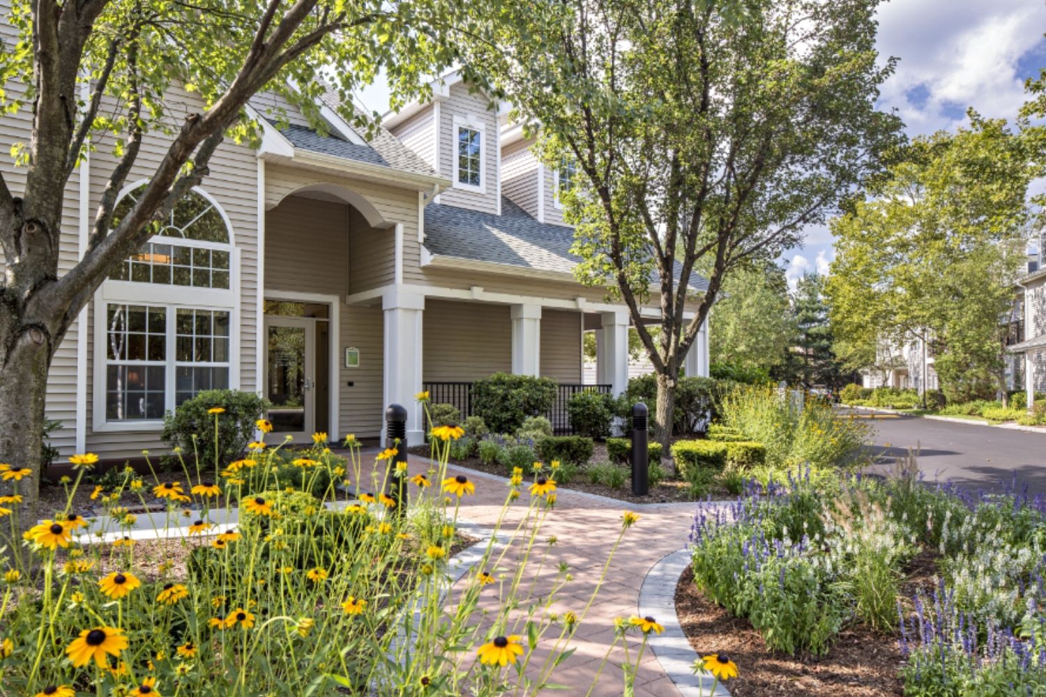 A quaint building surrounded by colorful flowers and lush greenery on a sunny day.