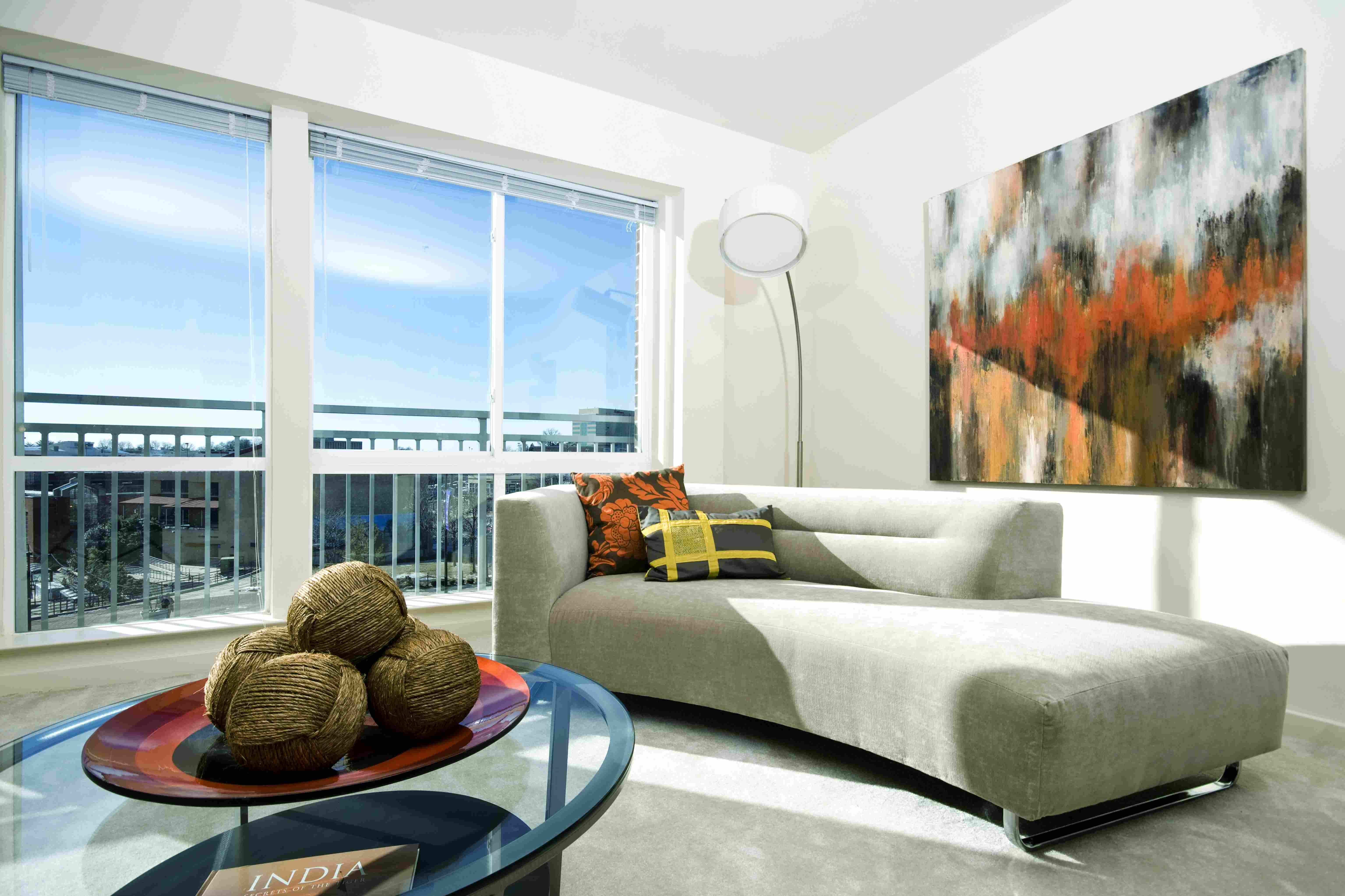Modern living room with a gray sofa, abstract art, and a large window letting in natural light.