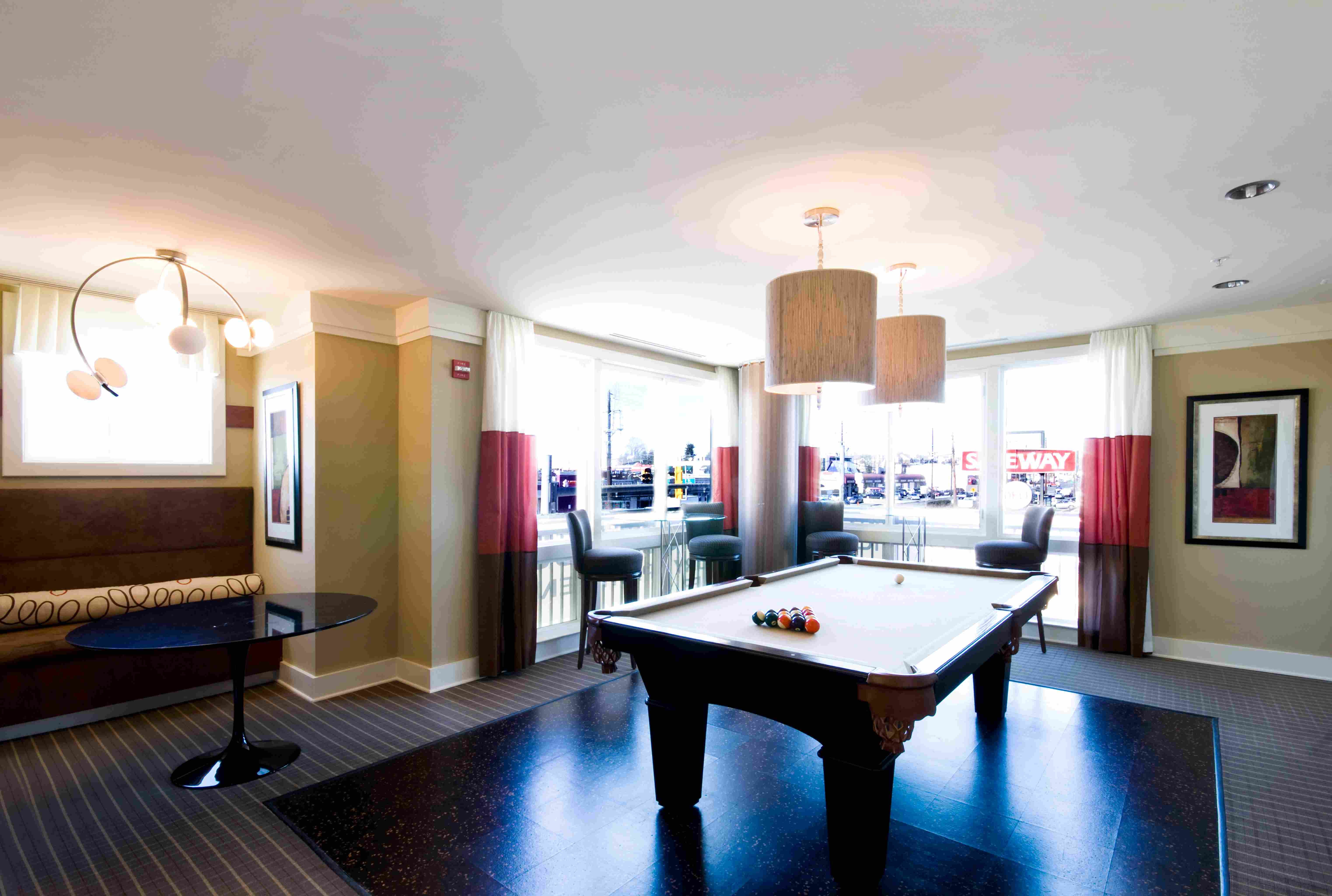 Bright lounge with a pool table and large windows, featuring modern decor.