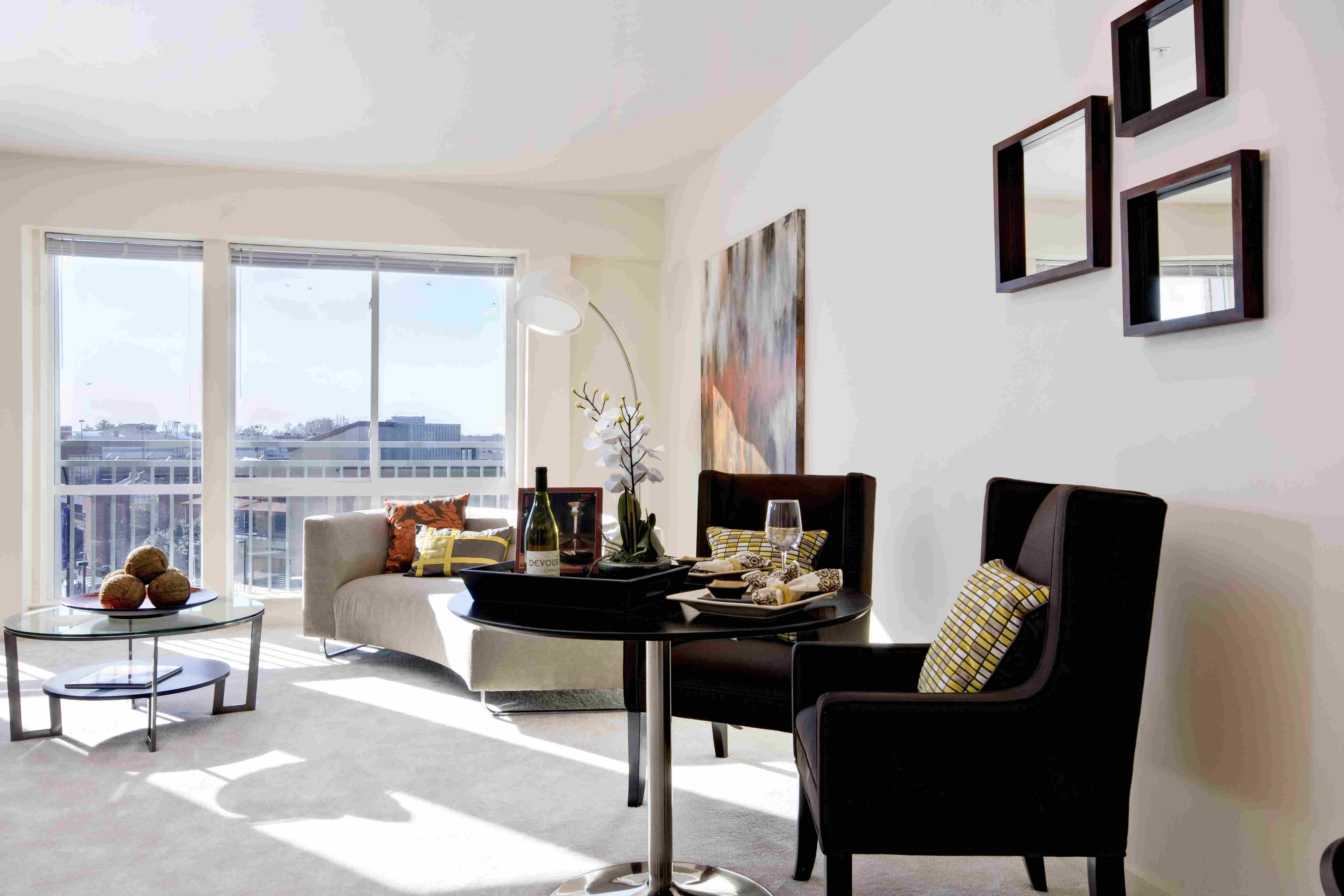 Modern living room with two chairs, a coffee table, and large windows overlooking a city view.