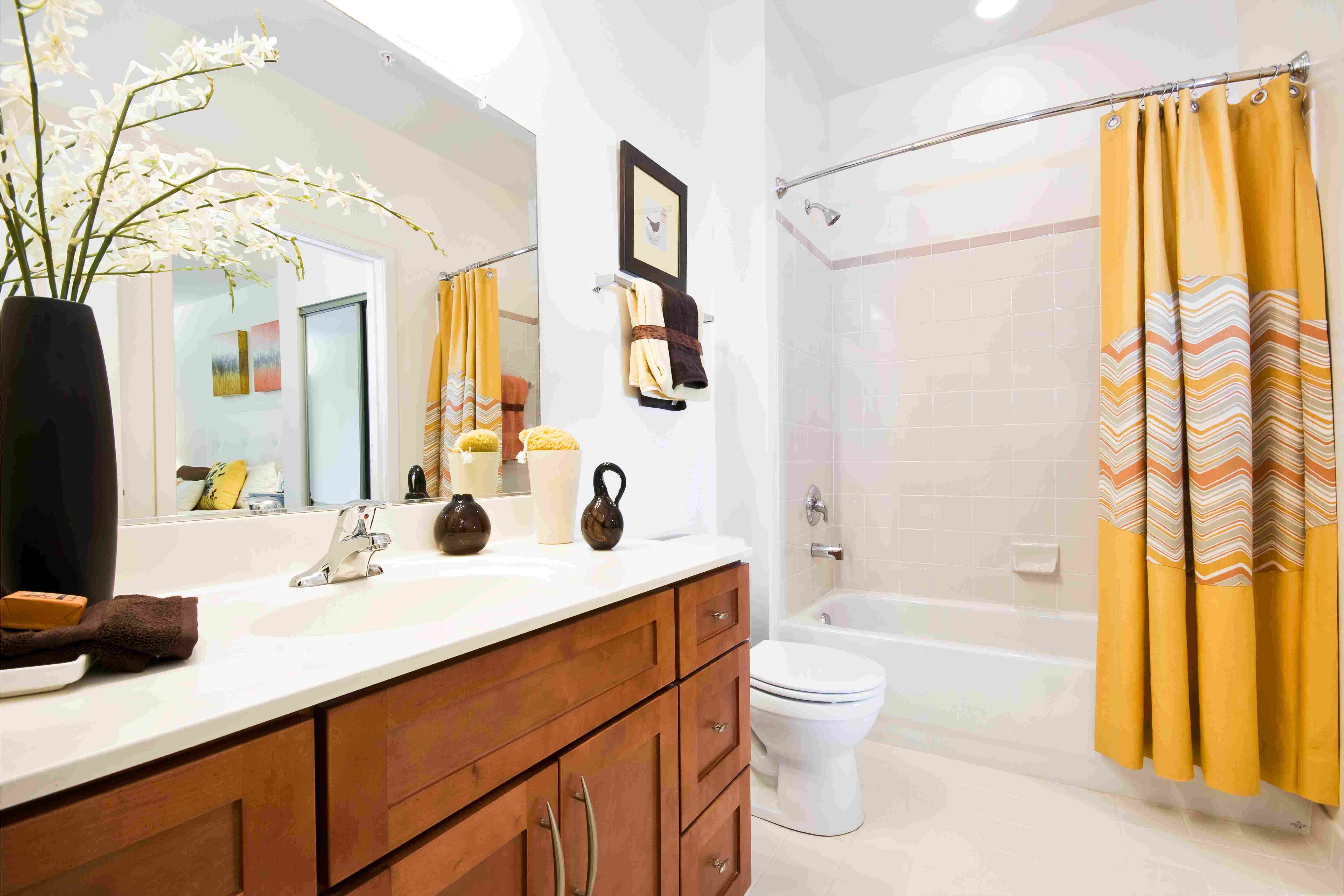 Bright bathroom with yellow curtains, wooden vanity, and modern fixtures.