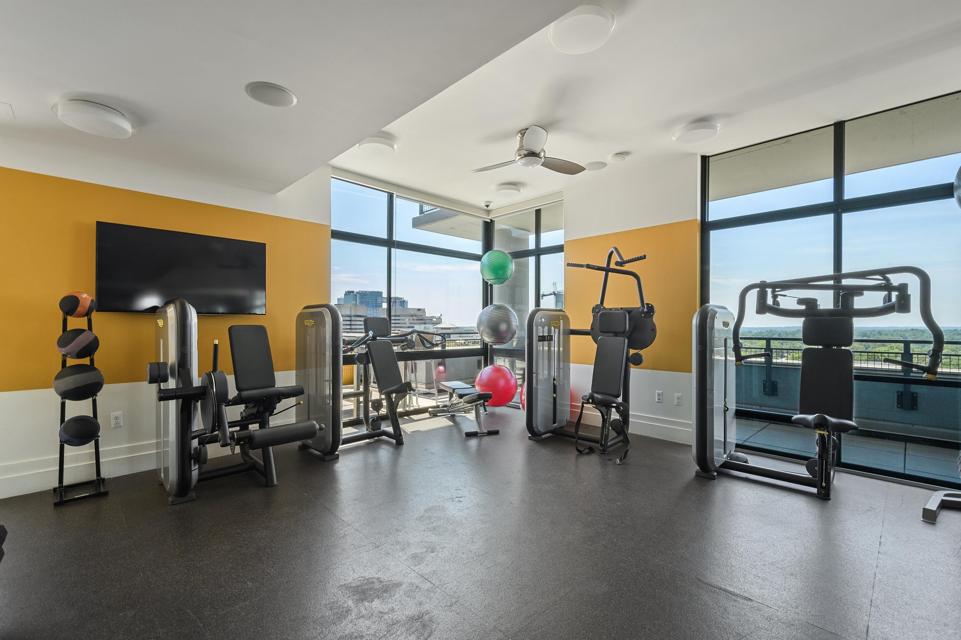 Modern gym with workout equipment and large windows overlooking a view.