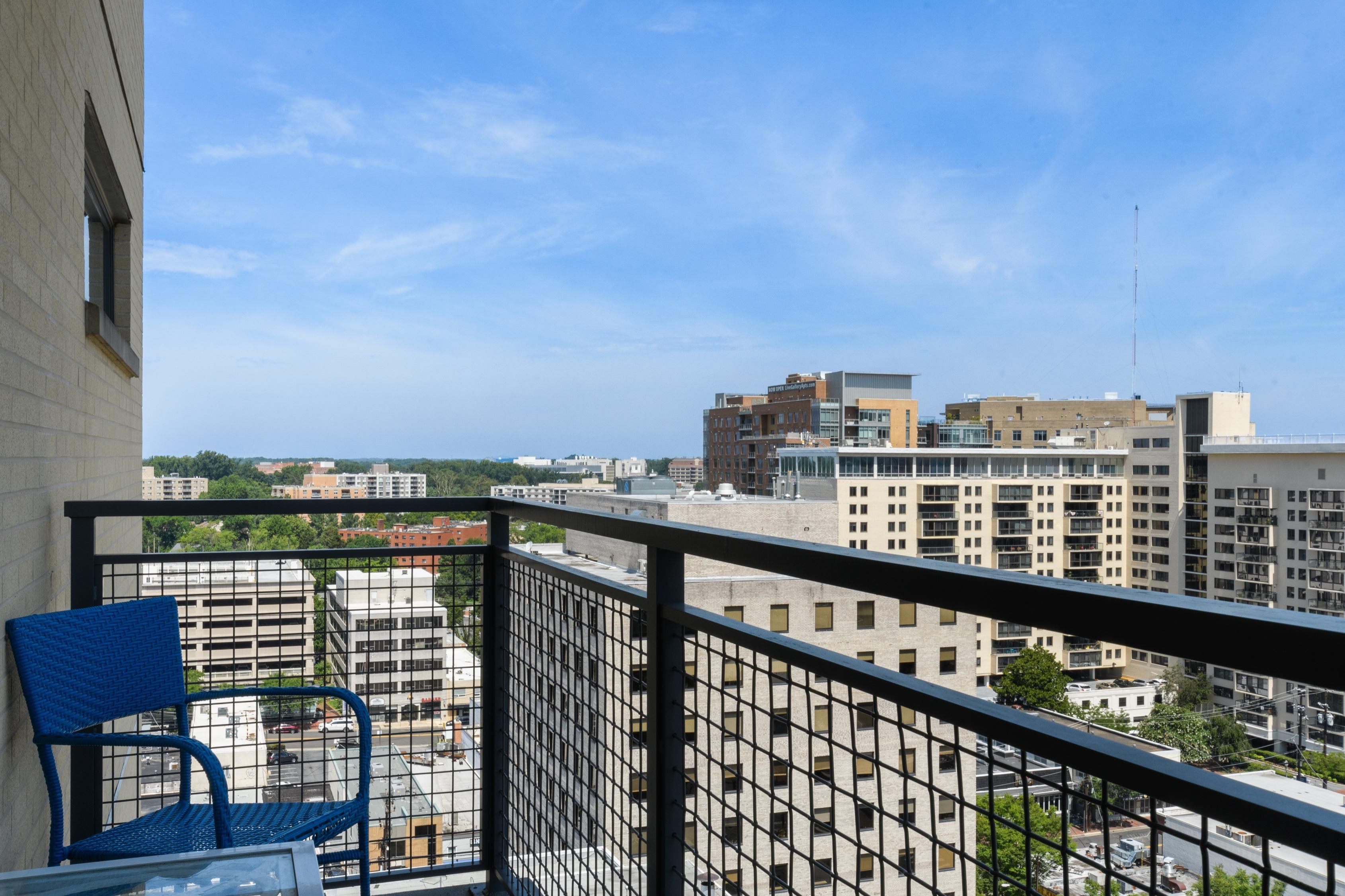 View from a balcony overlooking city buildings and blue sky.