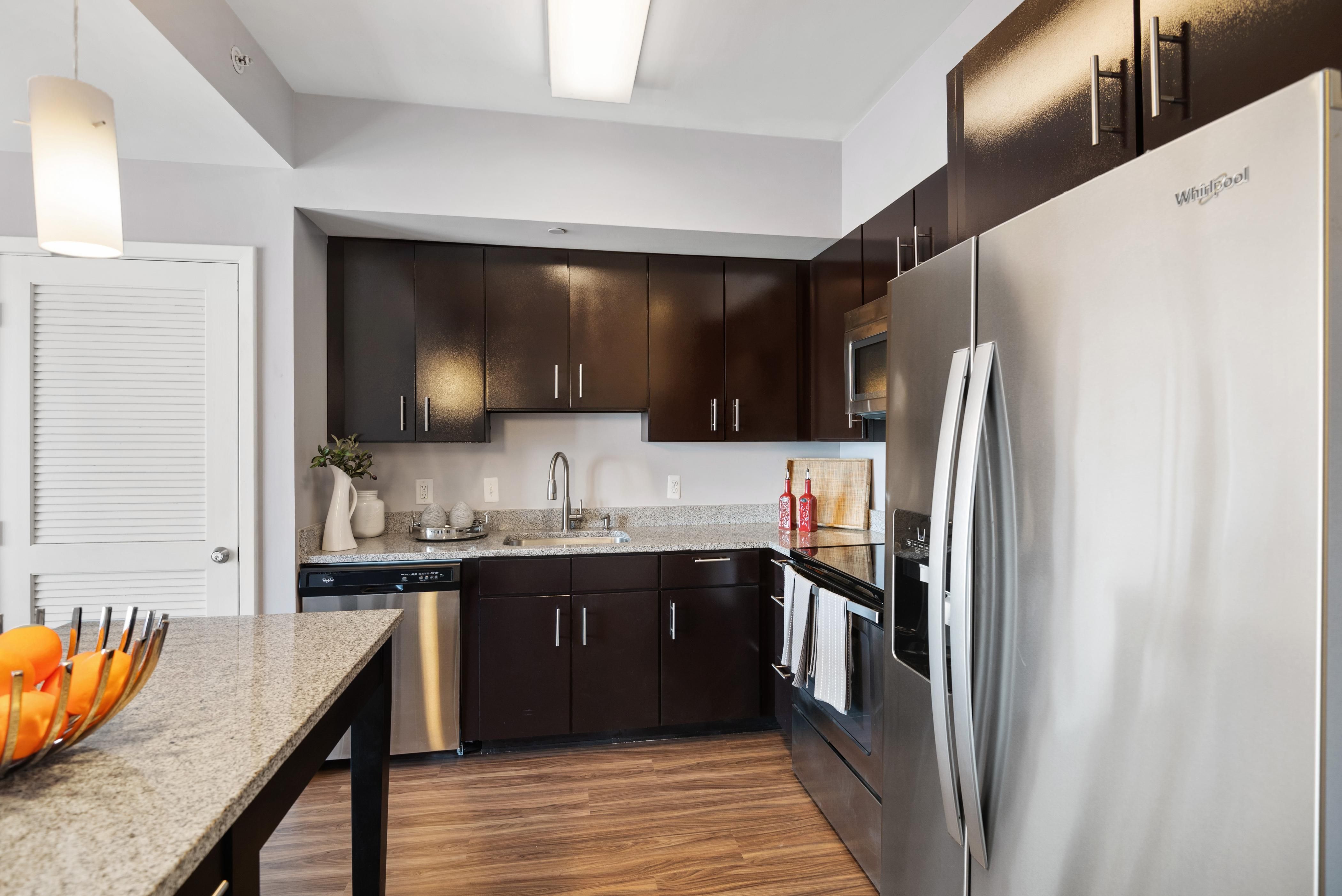 Modern kitchen featuring dark cabinets, stainless steel appliances, and a granite countertop.
