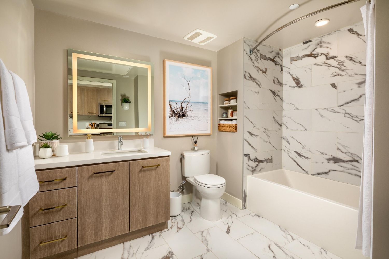Modern bathroom with a large mirror, marble accents, and a shower-tub combo.