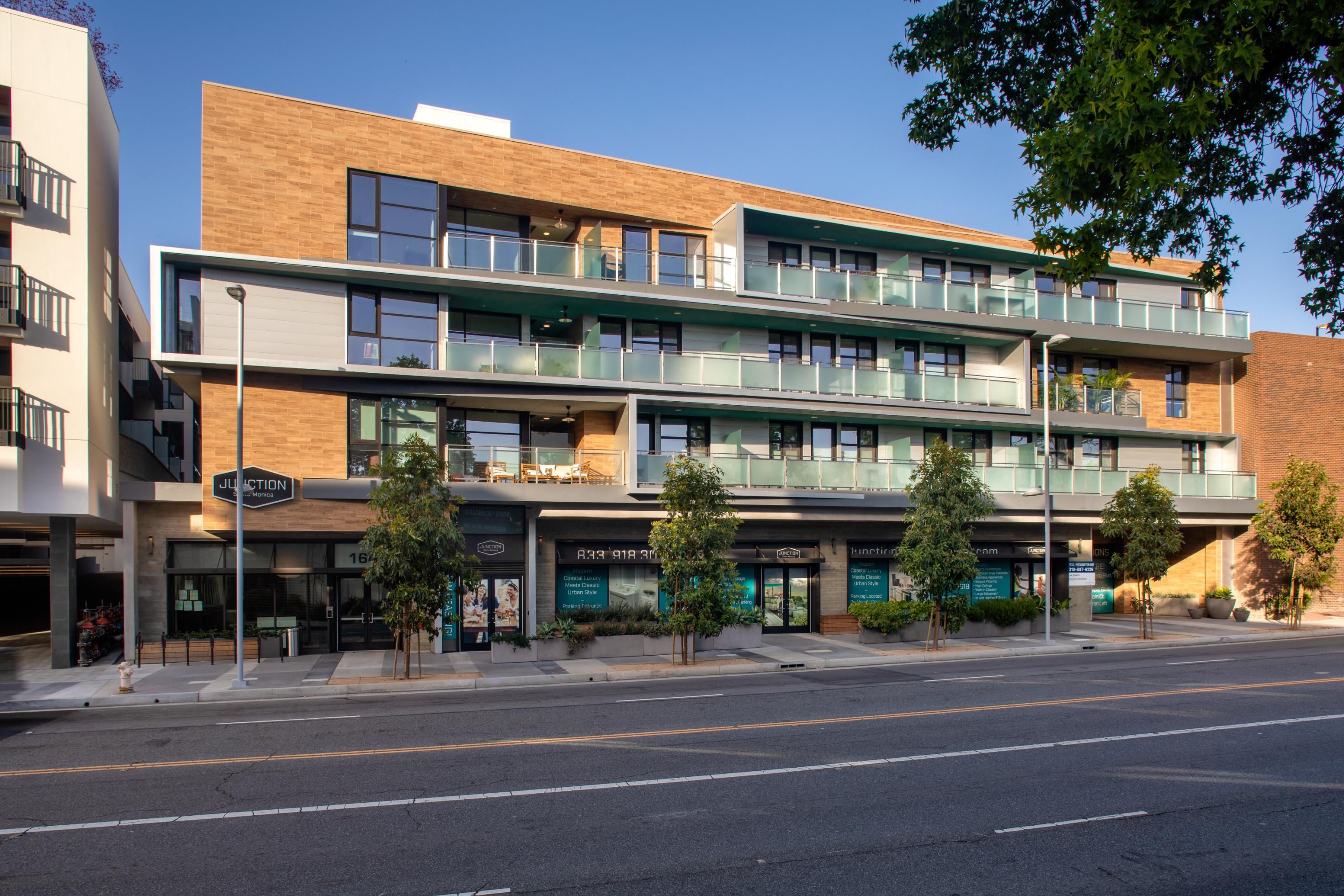 Modern multi-story building with balconies and storefronts on the ground floor.