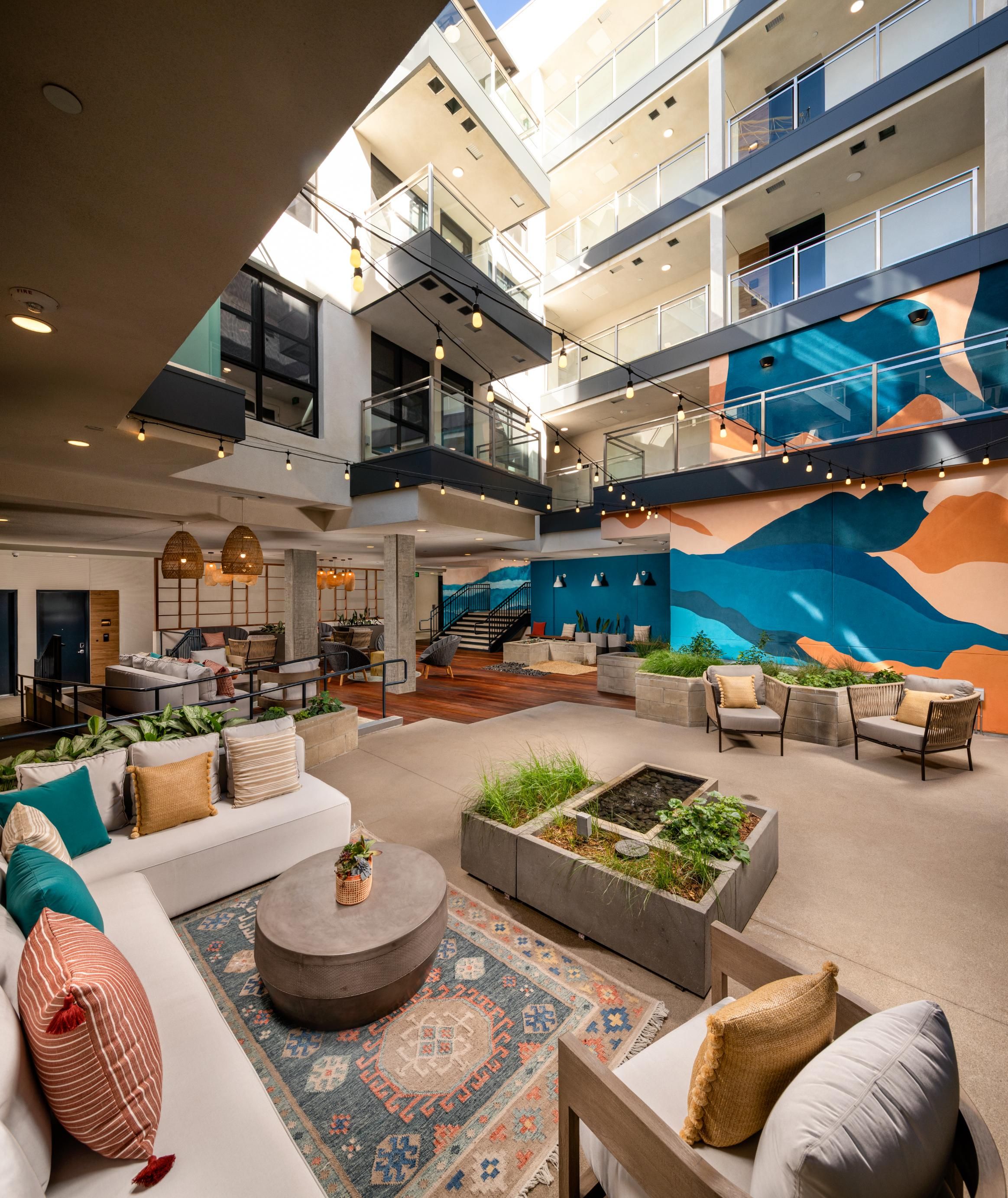 Bright, modern indoor space with couches, plants, and a colorful mural.
