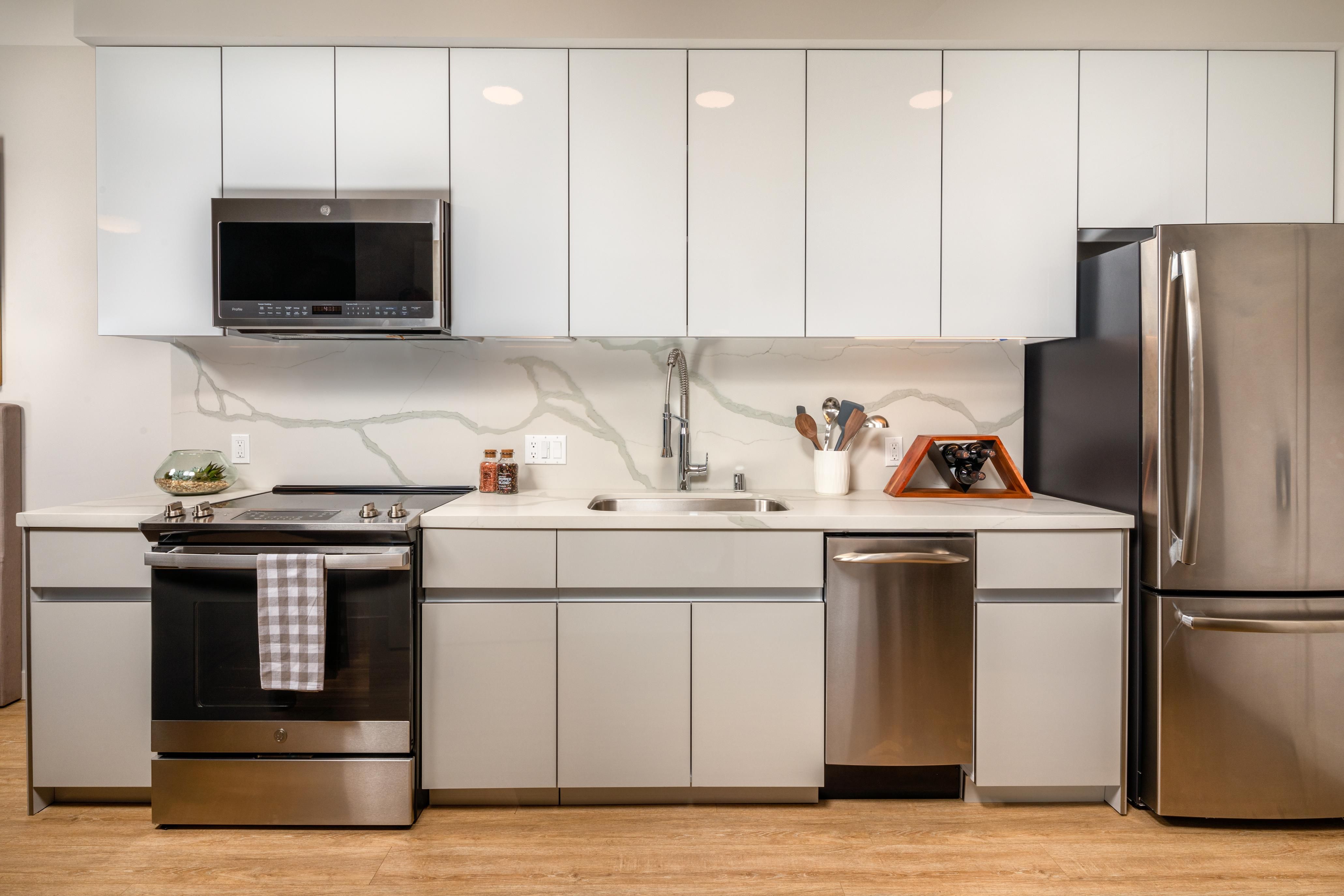 Modern kitchen with stainless steel appliances and white cabinetry.