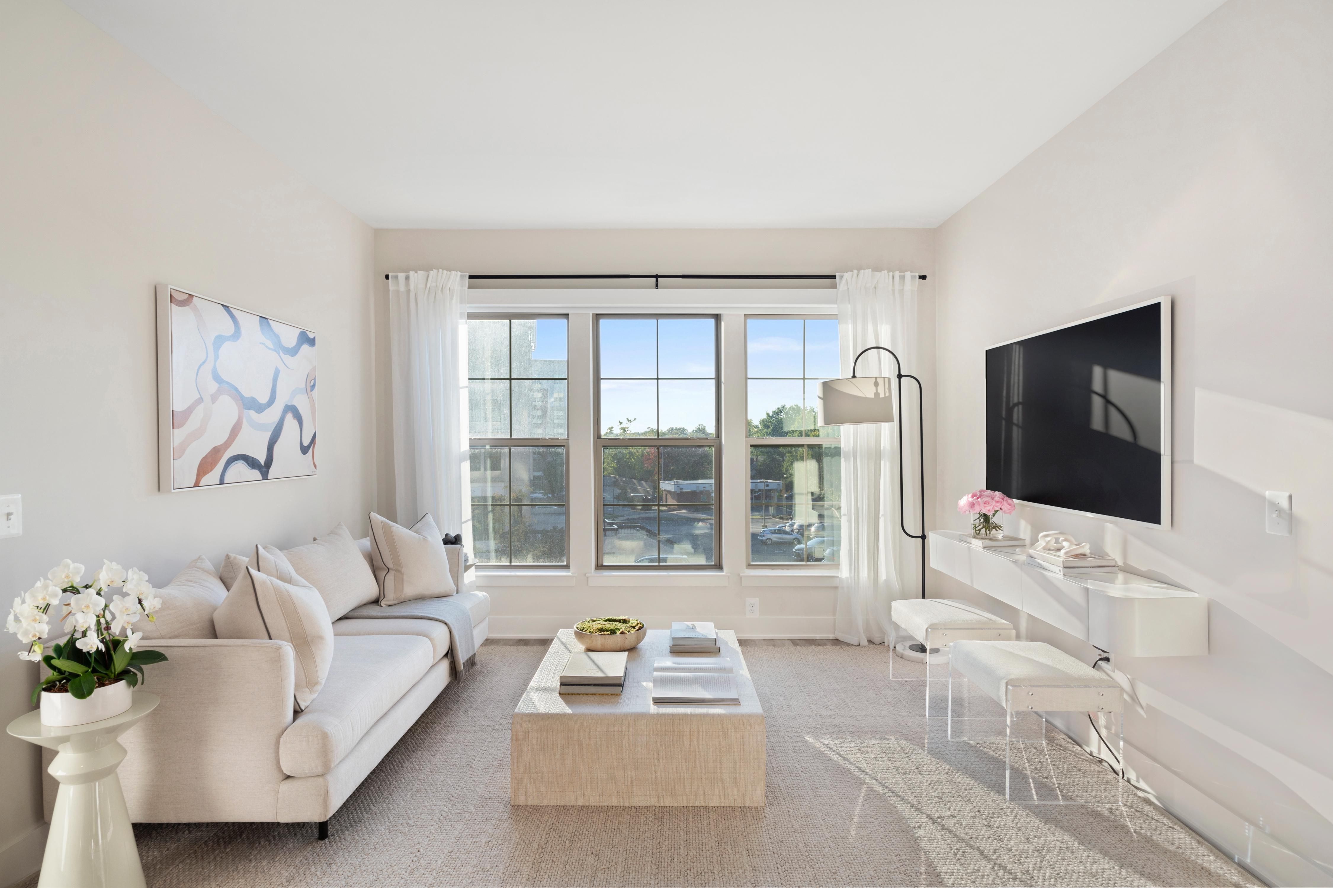 Modern living room with light colors, large windows, and minimal decor.