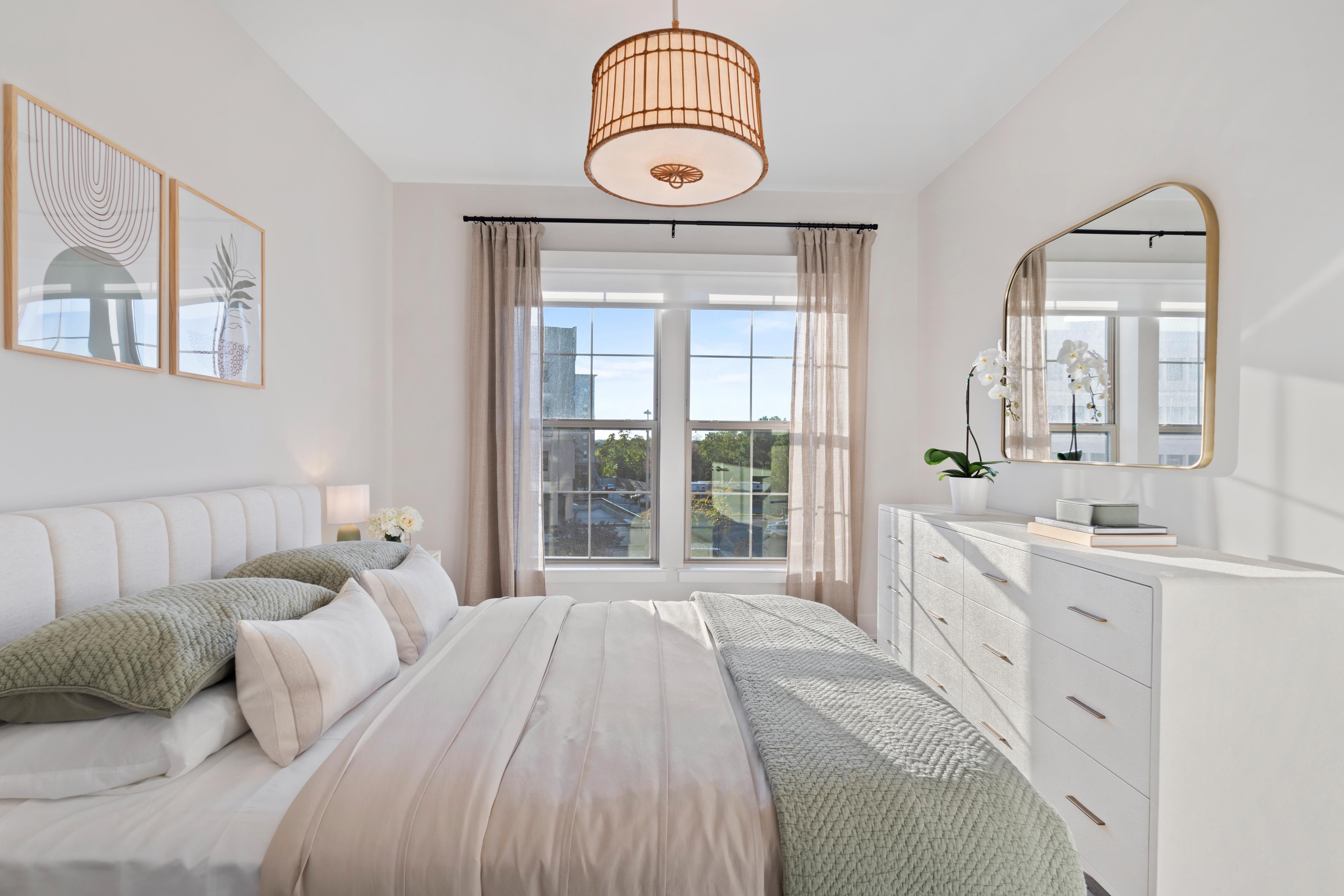 Cozy, modern bedroom with a large window, light curtains, and a neutral color palette.