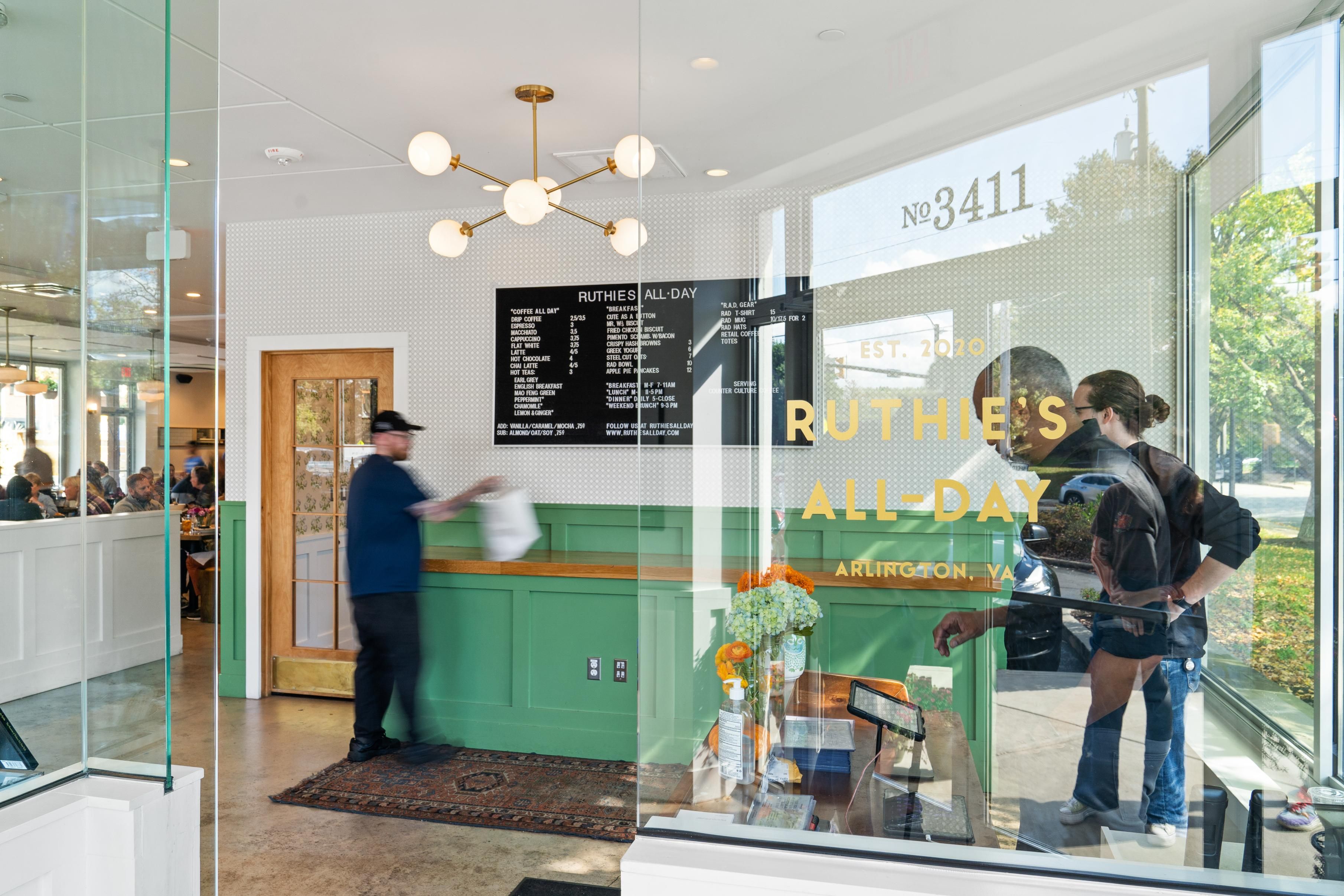 A modern café interior with a counter, menu board, and patrons.